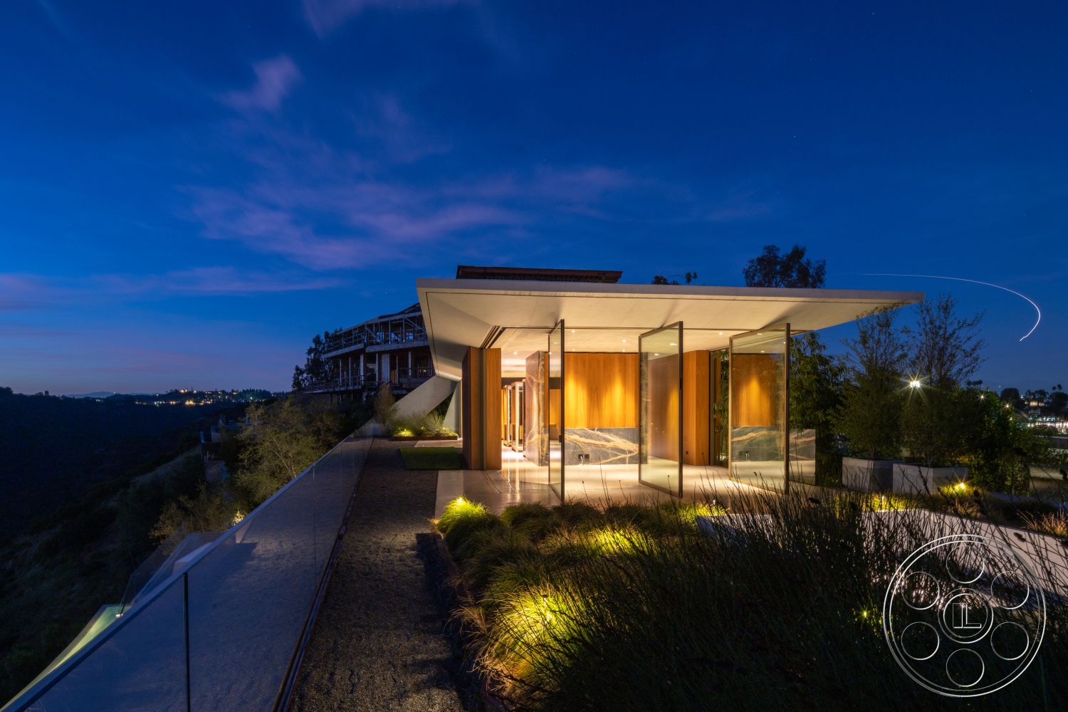 Modern 516 - exterior, flat roof, minimalist design, large glass doors, metal railing, nighttime setting, modern architectural style, mountain view, wood accent wall, outdoor lighting features, landscape garden, concrete patio flooring, glass exterior walls
