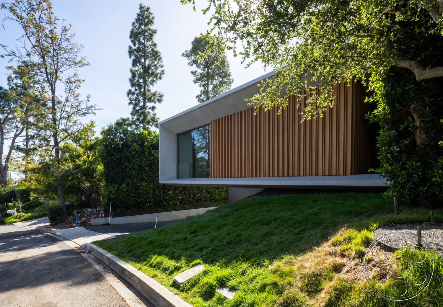 Modern 516 - exterior, flat roof, landscaped front yard, modern architectural style, curved driveway, large floor-to-ceiling windows, concrete foundation, grassy lawn area, wood slat siding, slightly elevated structure
