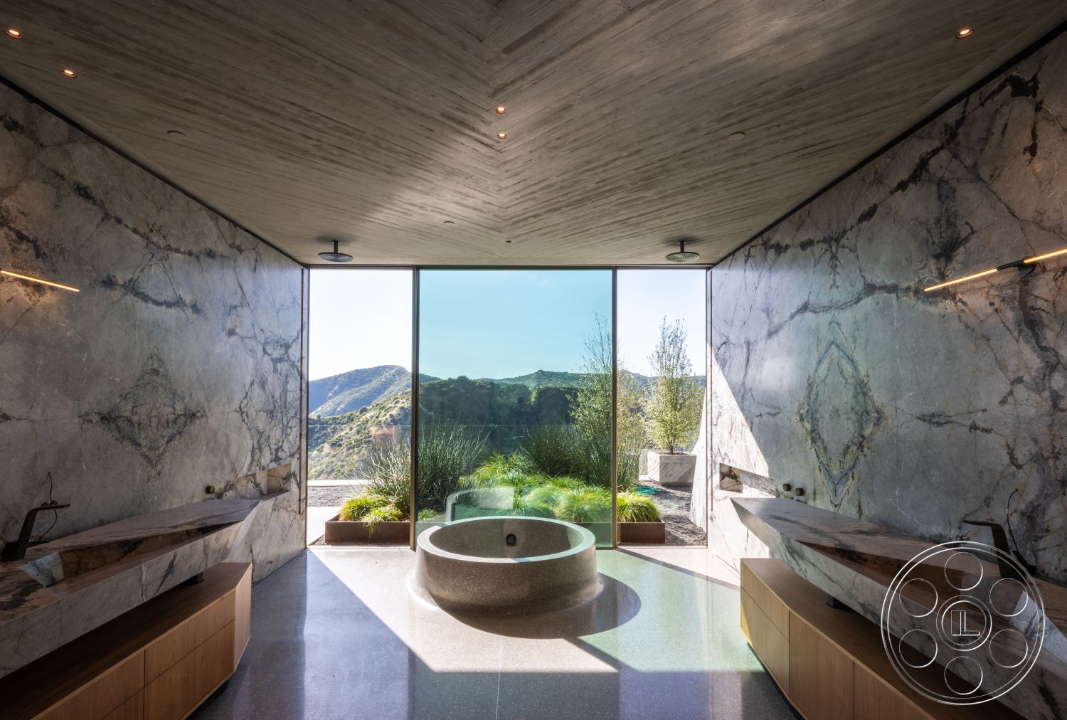 Modern 516 - polished concrete flooring, mountain view backdrop, textured wood beam ceiling, natural landscape integration, modern wall-mounted faucets, marble wall panels, linear wood vanities, round soaking tub, glass expansive windows