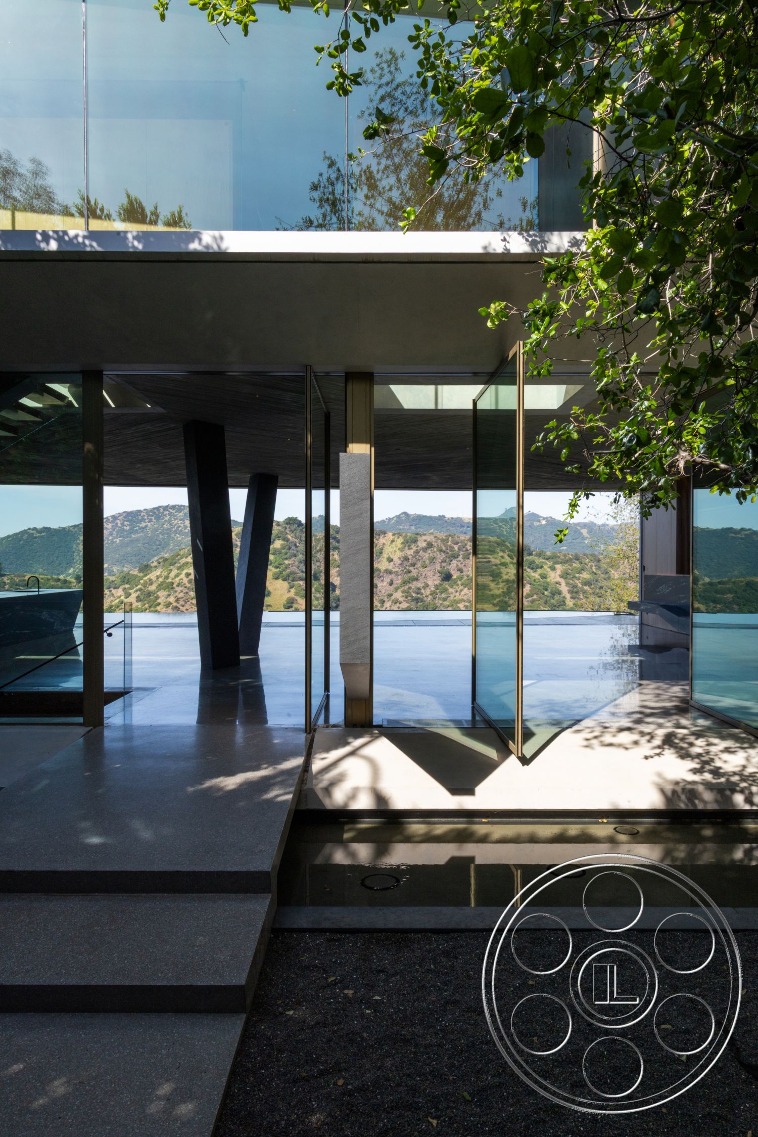 Modern 516 - exterior, glass sliding doors, concrete steps, modern architectural style, hillside location, floor-to-ceiling glass windows, landscaped gravel area, open outdoor terrace, polished concrete patio, metal framing structures
