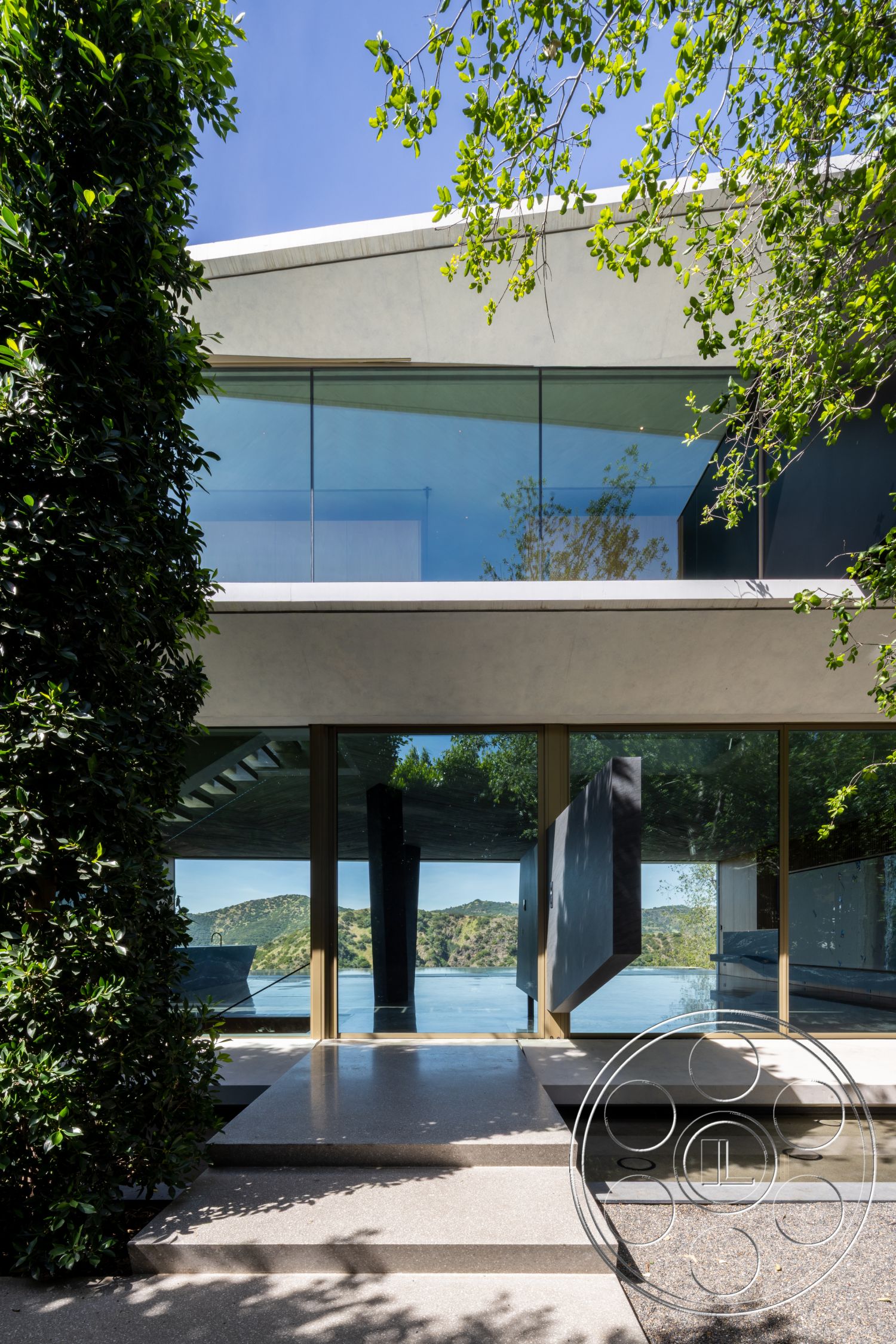 Modern 516 - exterior, sliding glass doors, landscaped greenery, glass windows, concrete facade, hillside location, flat roof design, minimalist architectural style, steel structural supports, polished concrete walkway, slab concrete entryway, lakefront view