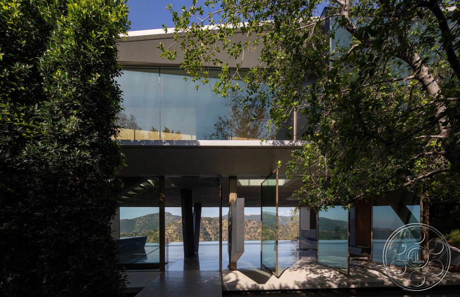 Modern 516 - exterior, flat roof, open floor plan, floor-to-ceiling windows, natural landscape, modern architectural style, wood deck, mountain view, overhanging eaves, concrete patio floor, integrated outdoor living space, concrete structural columns, expansive glass facade