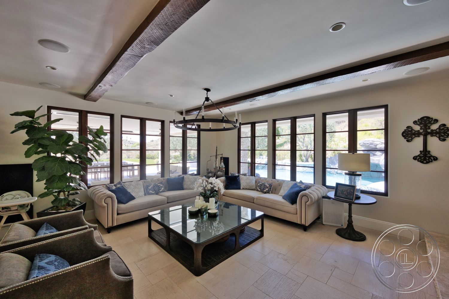 Hayden House - neutral color palette, large floor-to-ceiling windows, dark wood coffee table, cream-colored sectional sofa, indoor plant accent, modern chandelier lighting, tile living room flooring, light-colored painted walls, decorative wood beam ceiling, luxury fabric upholstery, decorative wall accent