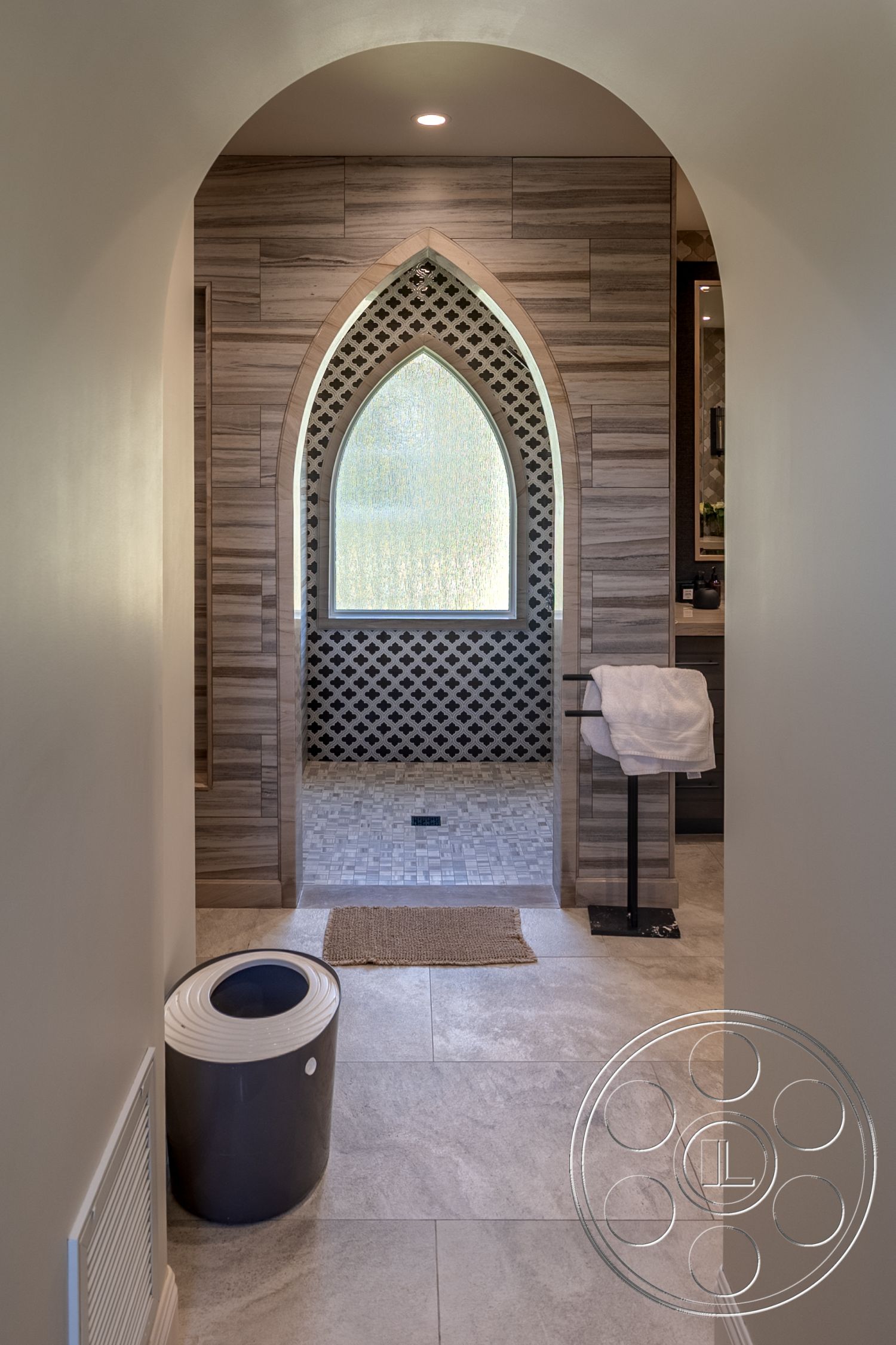 Hayden House - modern bathroom, woven area rug, arched doorway, natural light from window, decorative wall niche, textured wood paneling, minimalist bathroom accessories, black and white mosaic tile shower walls, large format porcelain floor tiles