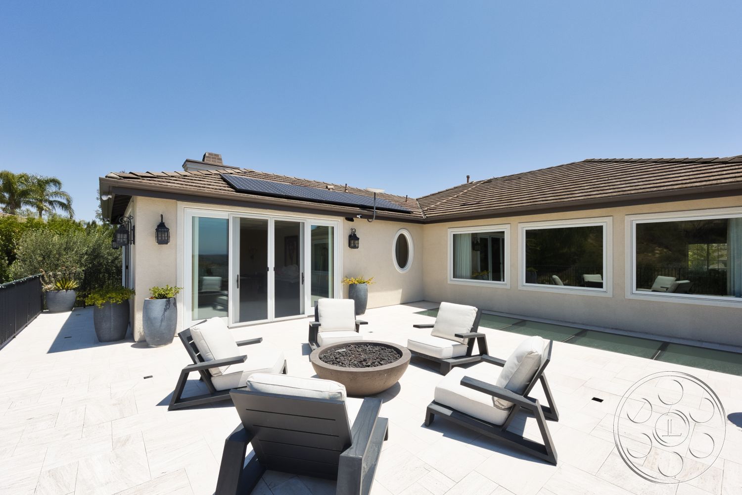 Hayden House - exterior, landscaped garden, aluminum railing, oval window, residential home, outdoor fire pit, modern lounge chairs, concrete patio flooring, sloped roof design, floor-to-ceiling glass sliding doors, solar panels on roof, desert home setting, slate tile patio surface, stainless steel outdoor lighting fixtures