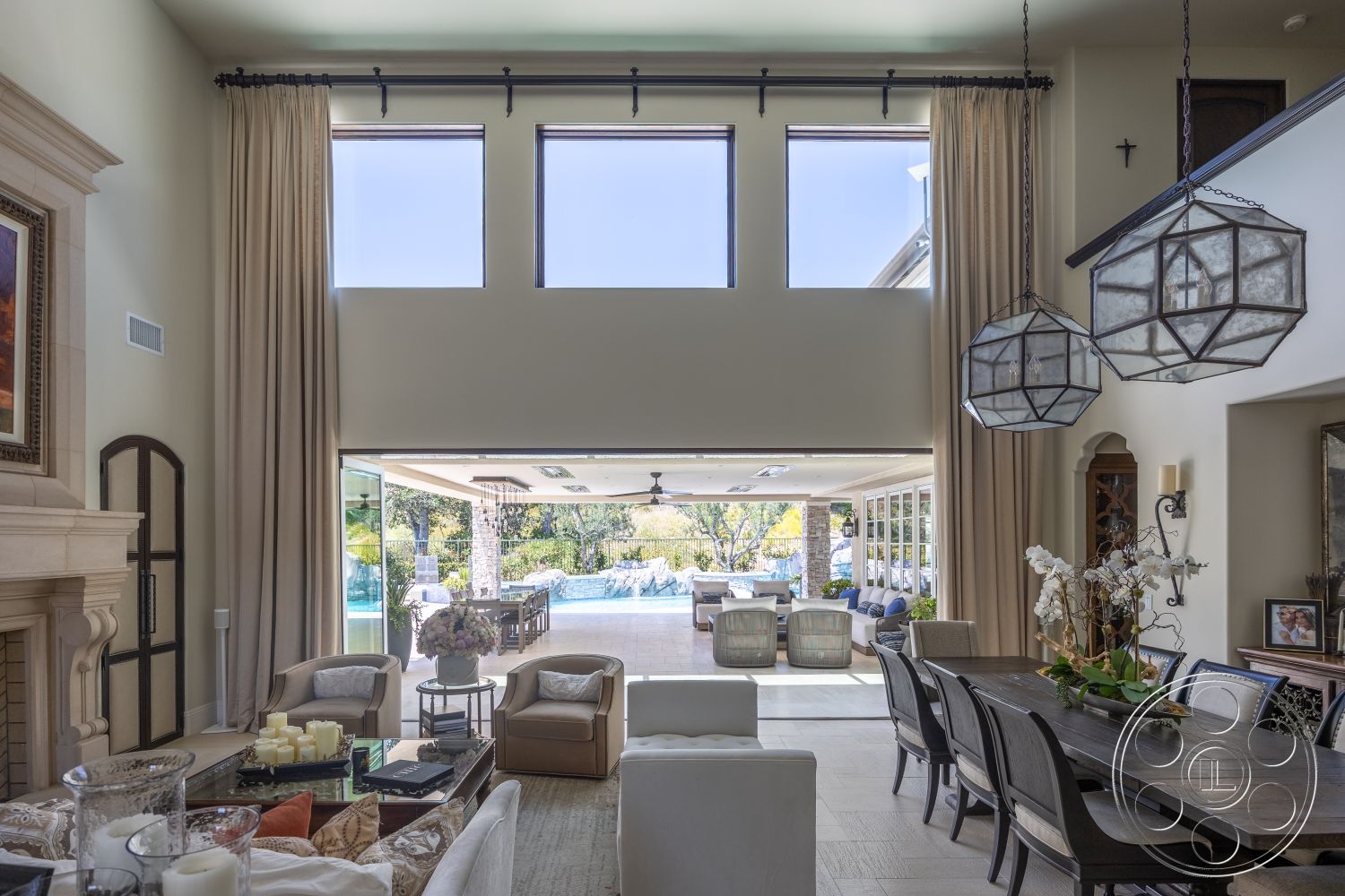 Hayden House - high ceilings, natural light, tile flooring, glass sliding doors, pool view, geometric pendant lighting, light wood dining table, rectangular windows, open concept living area, stone fireplace surround, modern outdoor seating area, upholstered beige armchairs, cream-colored drapes, potted orchids decor
