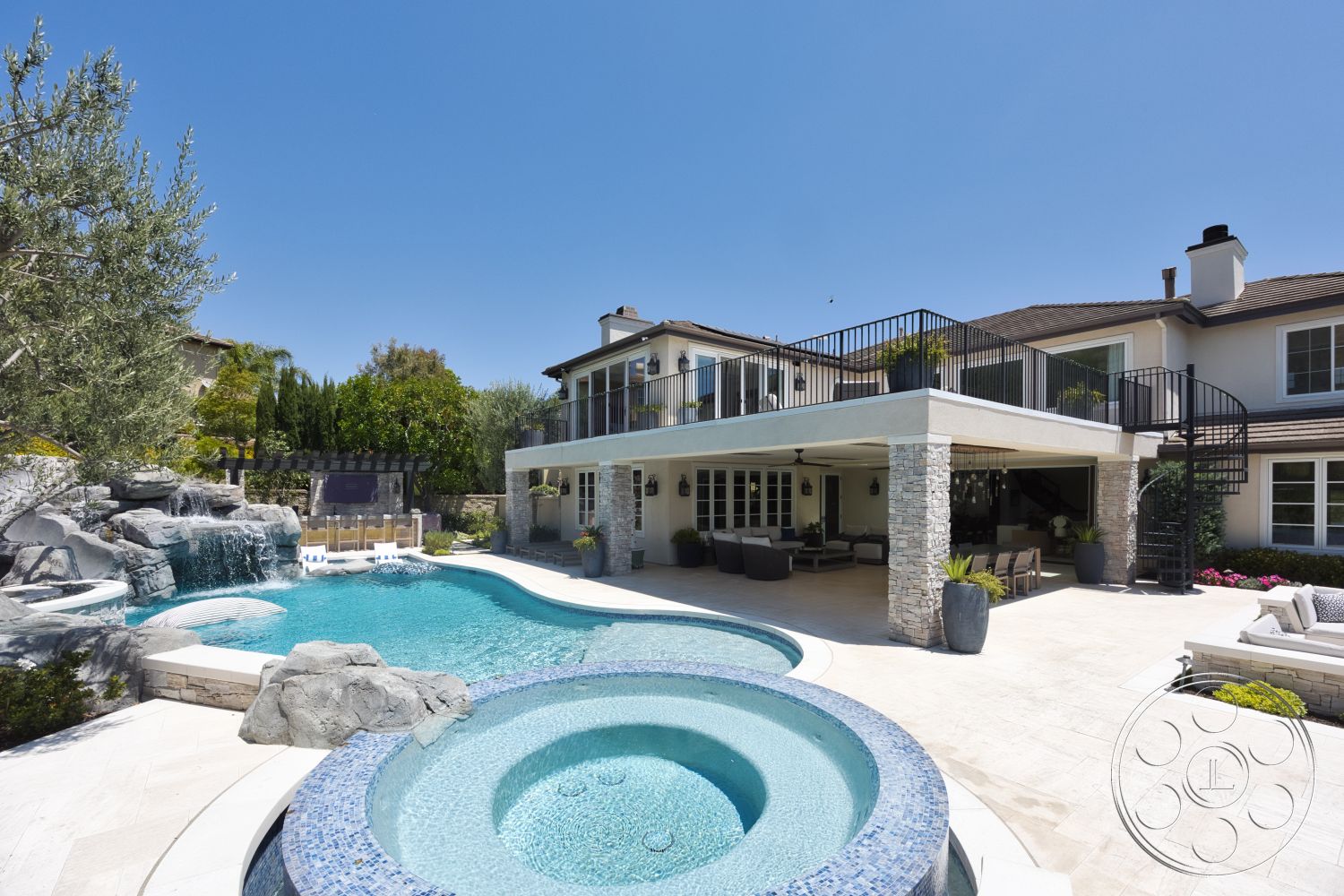 Hayden House - exterior, landscaped garden, glass sliding doors, outdoor seating area, circular hot tub, modern architectural style, rectangular pool, stone feature wall, waterfall feature, concrete patio flooring, sunny backyard setting, tile pool border, wooden balcony railing, metal spiral staircase