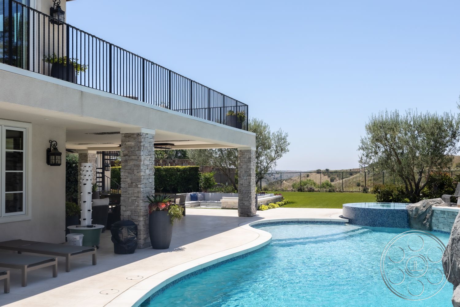Hayden House - exterior, landscaped garden, outdoor seating area, rectangular swimming pool, lagoon-style pool, hillside location, stone columns, stone pool deck, concrete patio flooring, glass balcony railing, plaster exterior walls, seating area under patio