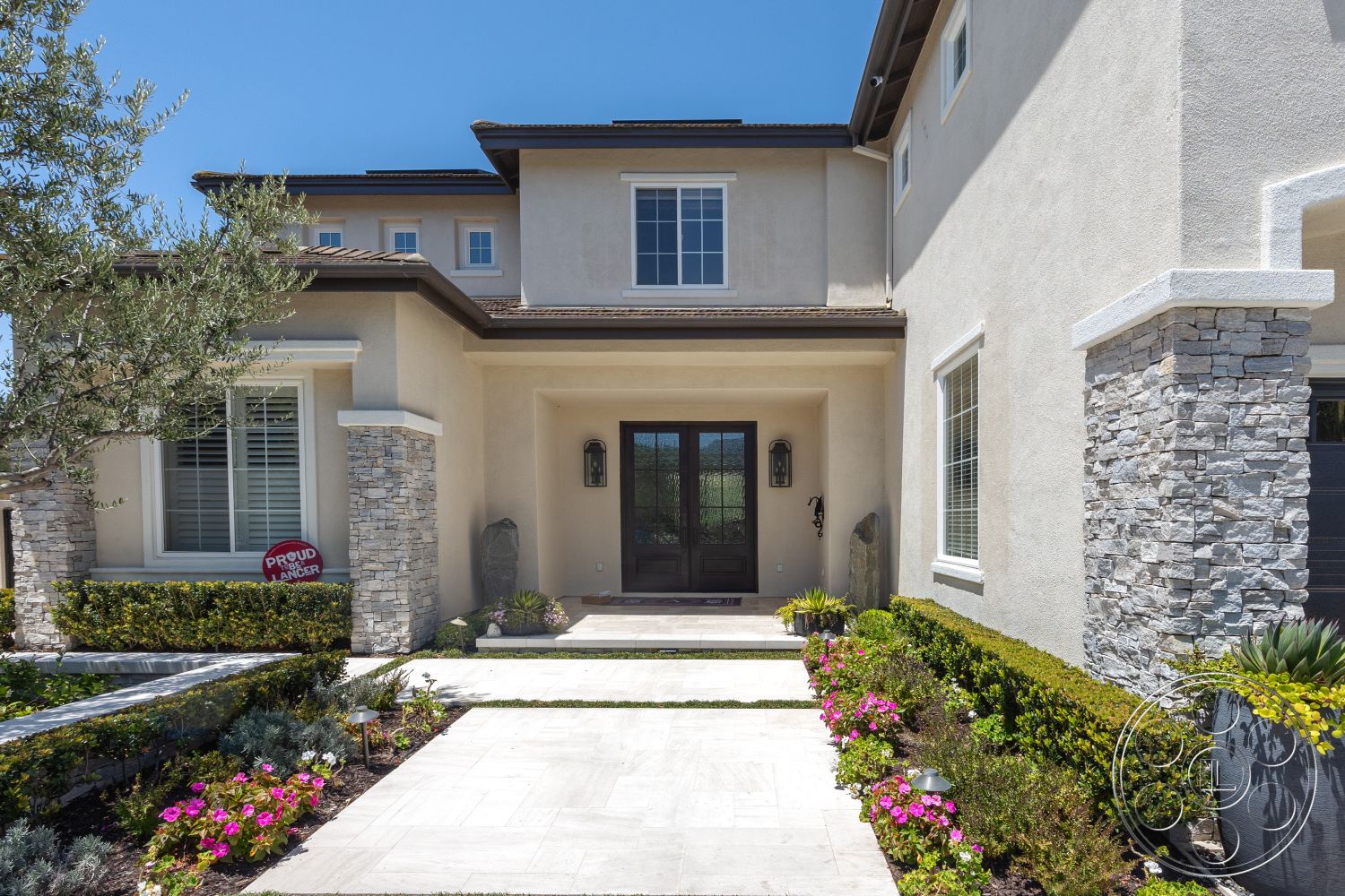 Hayden House - exterior, circular driveway, paved walkway, stucco walls, slate roof, decorative outdoor lighting, natural stone columns, concrete patio flooring, landscaped garden beds, horizontal window design, rectangular entryway, hedge border landscaping, double-door entrance, flowering garden plants