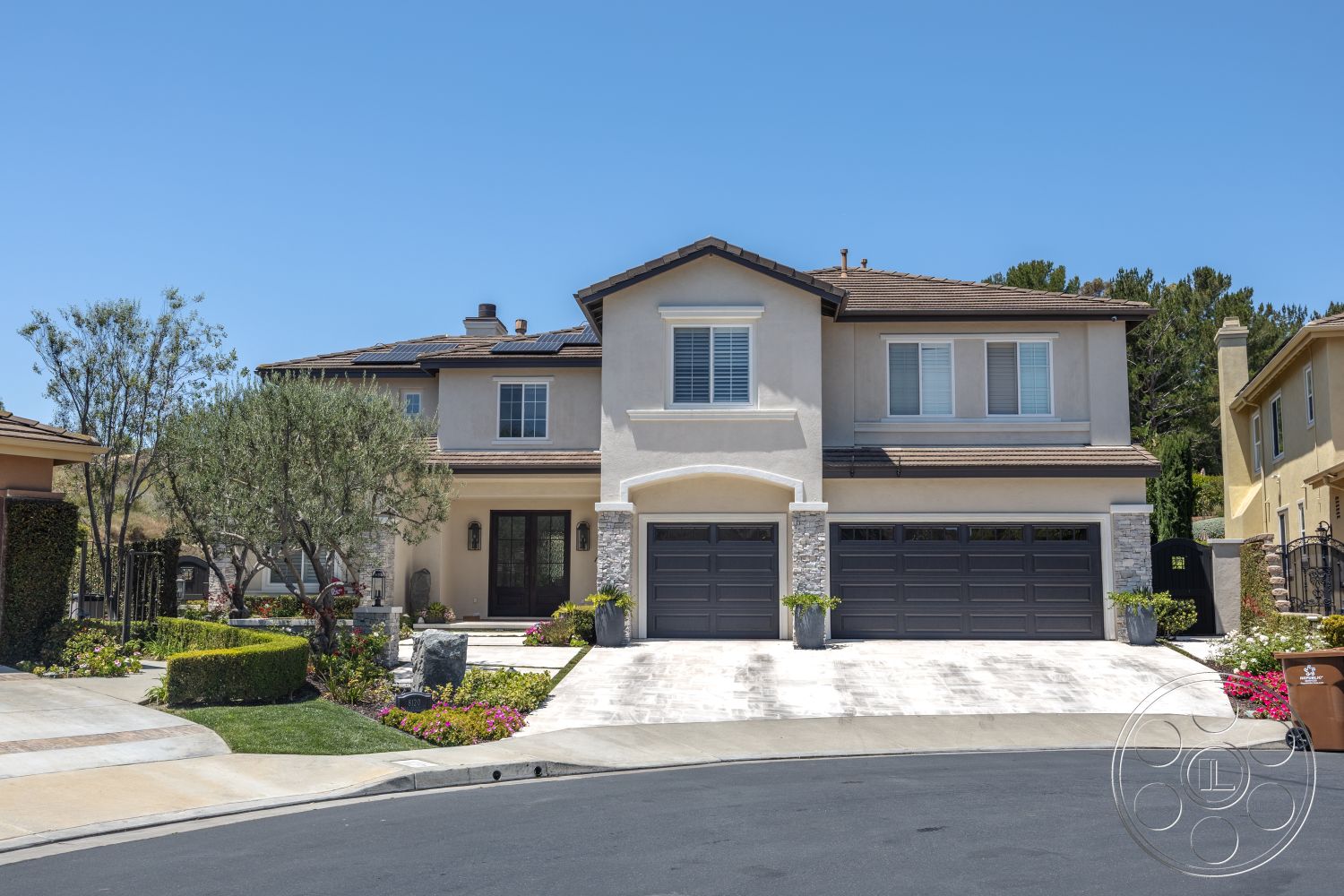 Hayden House - exterior, paved driveway, stone accent wall, decorative planters, modern architectural style, lawn area, gabled roof, curved driveway, stucco walls, two-story home, landscaped garden beds, asphalt shingle roofing, neighborhood setting, laminate garage doors, bright flower beds