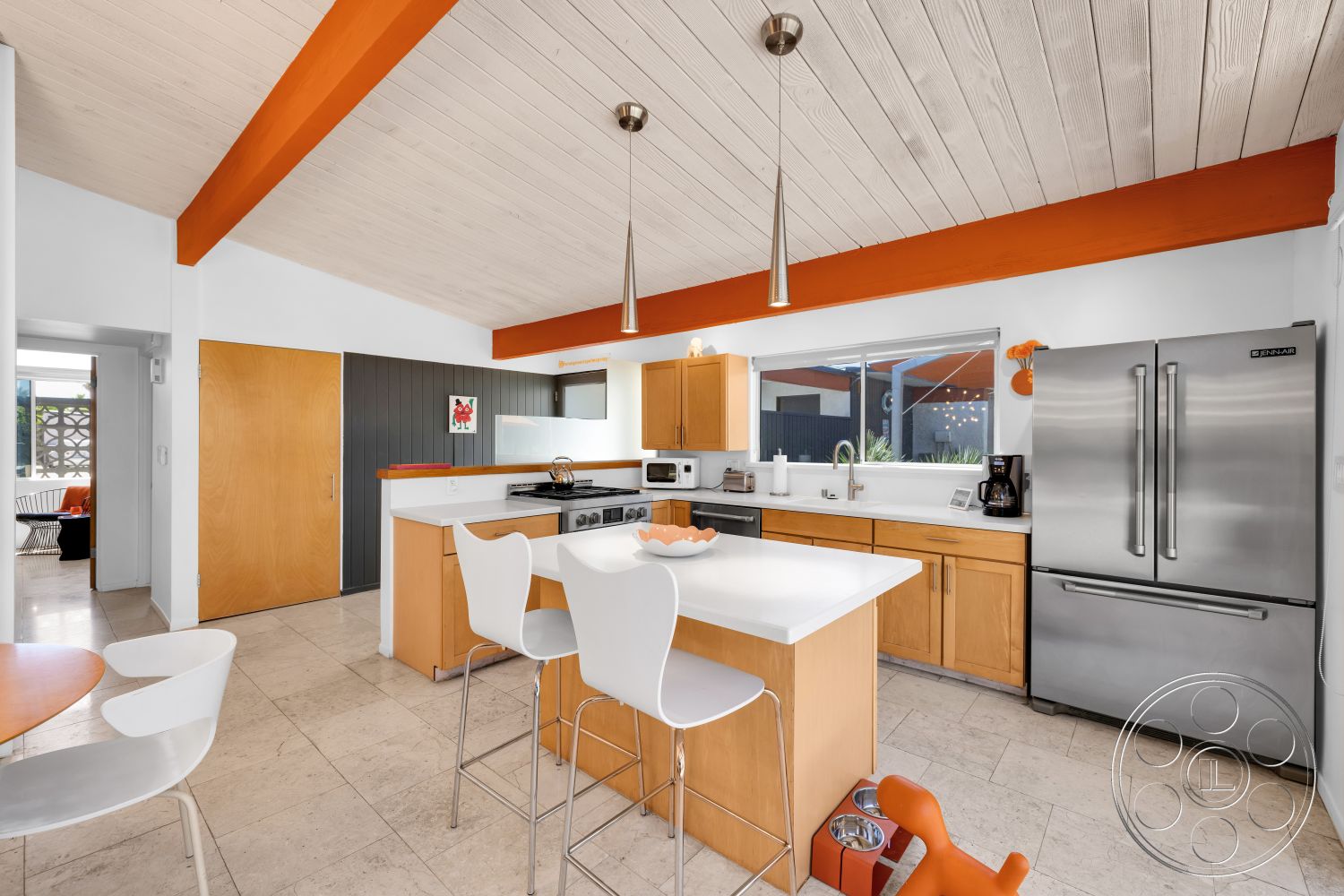 Palm Springs 76 - stainless steel appliances, light wood cabinetry, gray accent wall, pendant lighting fixtures, modern kitchen design, open concept kitchen, white quartz countertops, marble tile flooring, exposed wood ceiling, breakfast bar with white stools, orange painted beams, large kitchen window, inground countertop oven