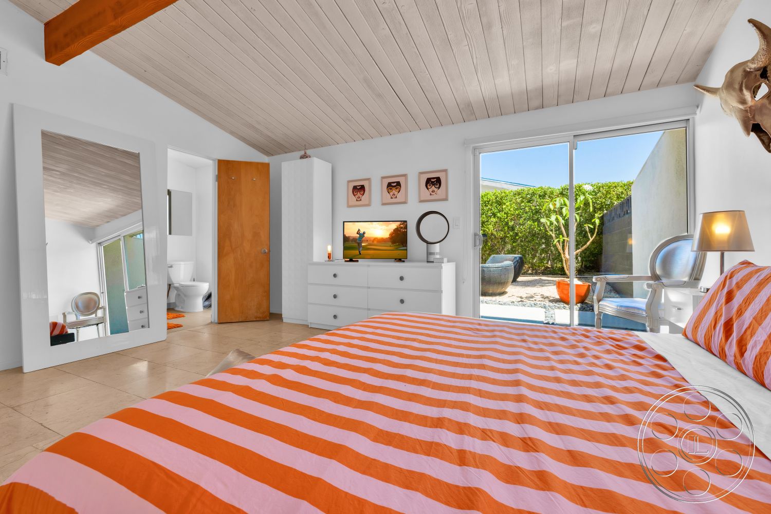 Palm Springs 76 - minimalist decor, natural light, exterior, garden view, indoor-outdoor living, reflective mirror, modern dresser, wood beam ceiling, white painted walls, outdoor patio area, tile bedroom flooring, contemporary style bedroom, large sliding glass door, colorful striped bedding