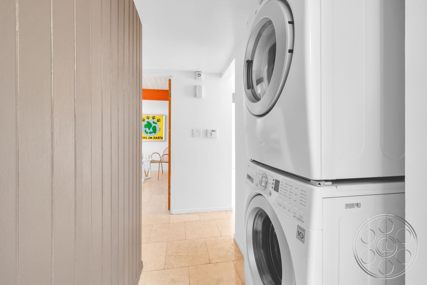 Palm Springs 76 - natural light, modern design, colorful wall art, painted white walls, open hallway, beige tile flooring, textured panel wall, stackable washer and dryer