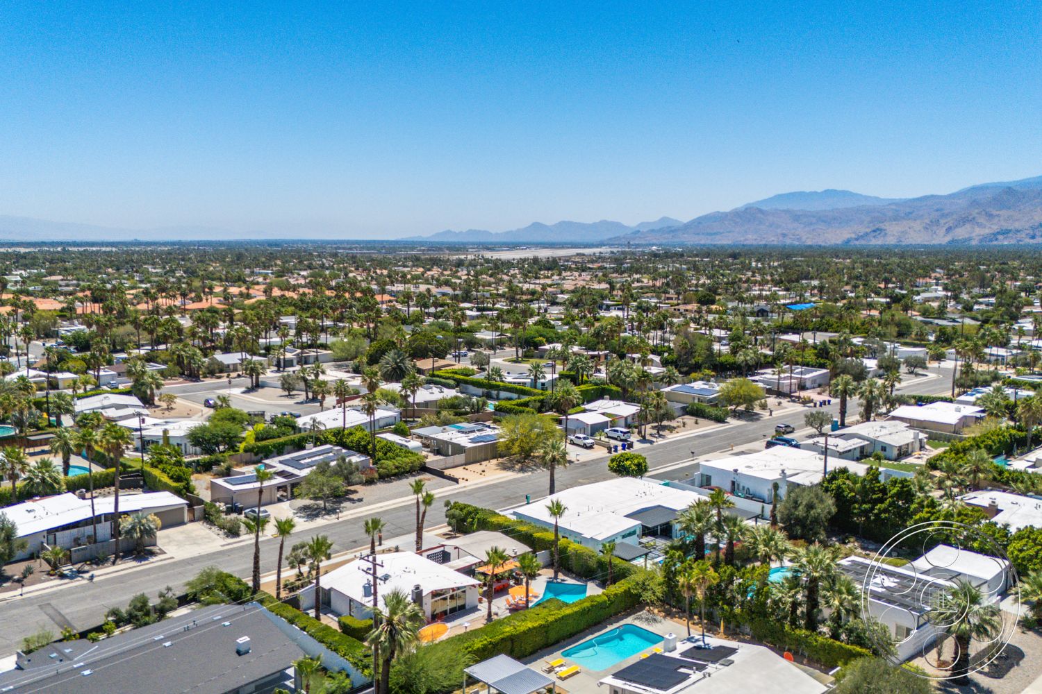 Palm Springs 76 - exterior, residential neighborhood, green hedges, mountain backdrop, desert setting, flat roofs, palm trees landscaping, single-story homes, concrete driveways, rectangular swimming pools, suburban streetscape, urban garden areas
