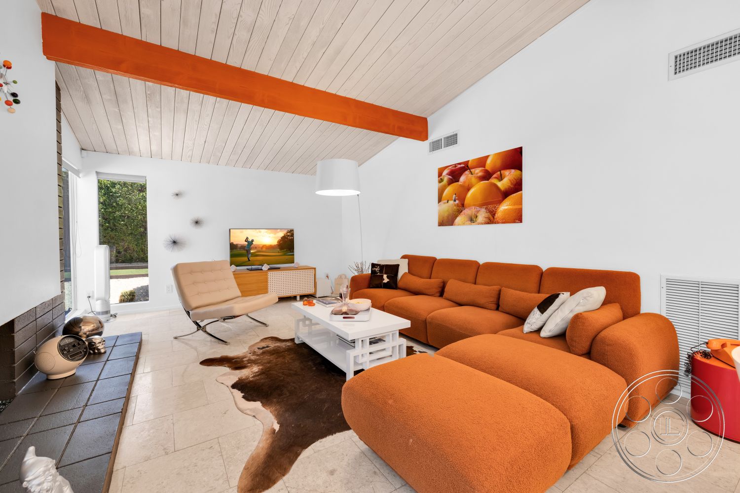 Palm Springs 76 - colorful wall art, floor-to-ceiling windows, vaulted ceiling, open living space, beige stone flooring, contemporary armchair, white coffee table, exposed wood ceiling beams, modern sectional sofa, orange accent beams, light-colored wood paneling, textured stone fireplace surround