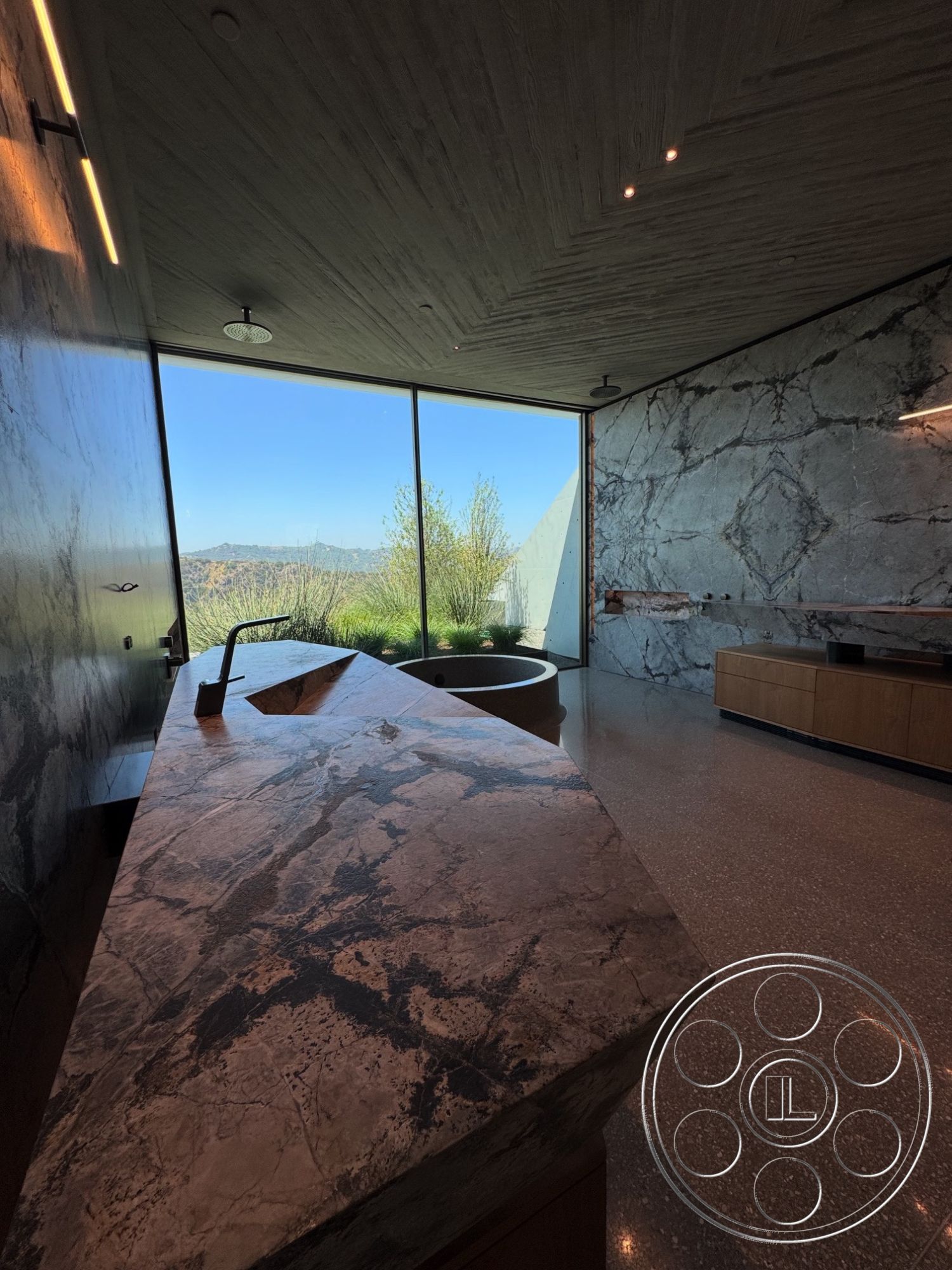 Modern 516 - wood cabinetry, textured plaster ceiling, under-cabinet lighting, concrete floor finish, modern geometric shapes, round soaking tub, polished marble kitchen countertop, glass wall with mountain view, angular kitchen island