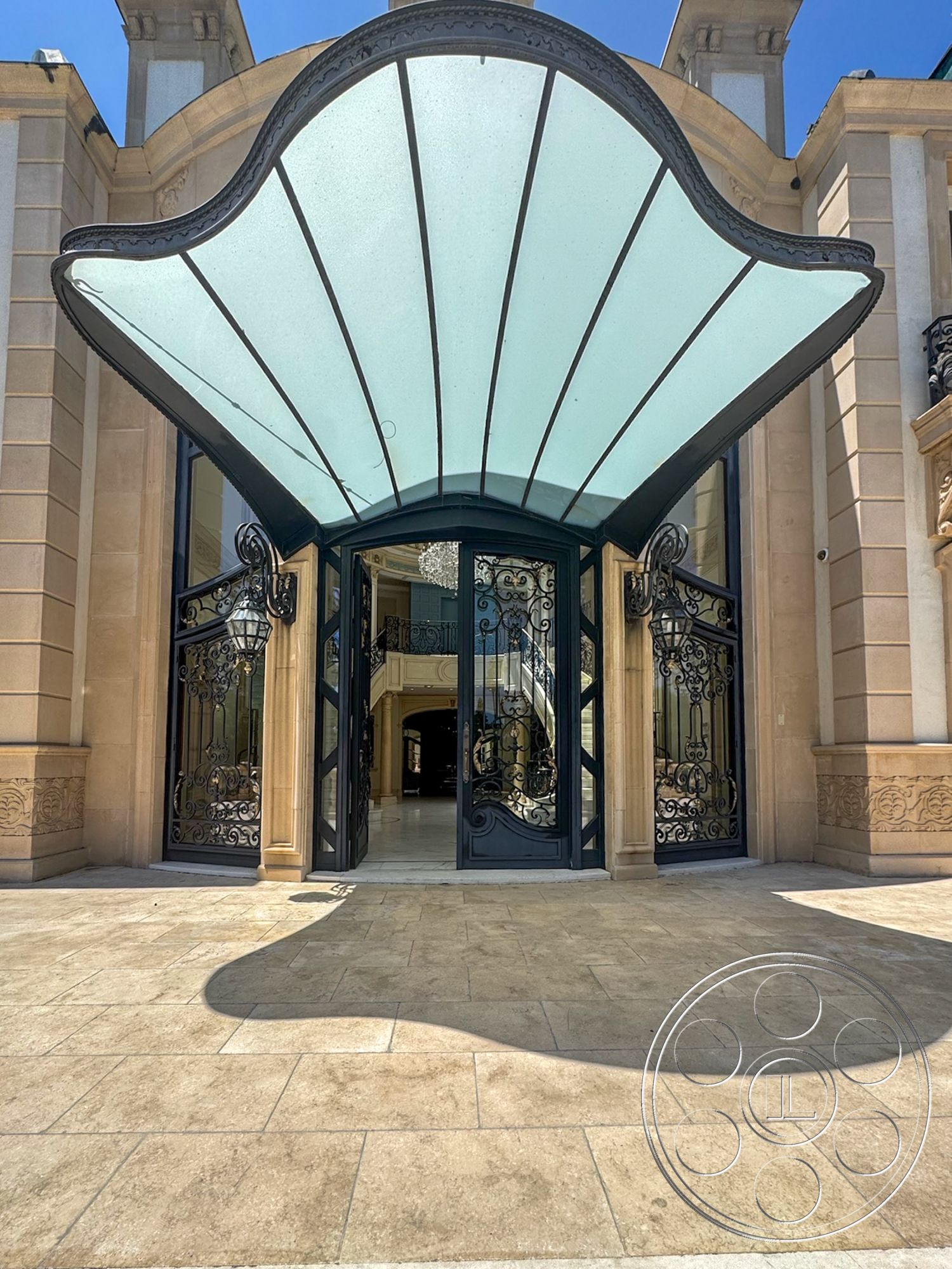 Tiffany Estate - exterior, modern architectural style, arched doorways, spacious entryway, textured stone floor, glass entrance canopy, ornate wrought iron doors, limestone facade, elaborate decorative moldings, luxurious entrance design