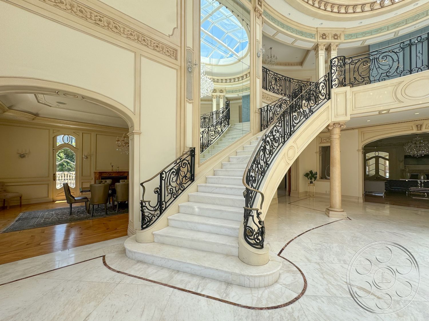 Tiffany Estate - high ceilings, coffered ceiling, wood paneling, chandelier lighting, marble flooring, arched doorways, elegant dining area, intricate moldings, curved staircase, natural light from skylight, iron balustrade railing, plaster wall detailing, circular foyer design