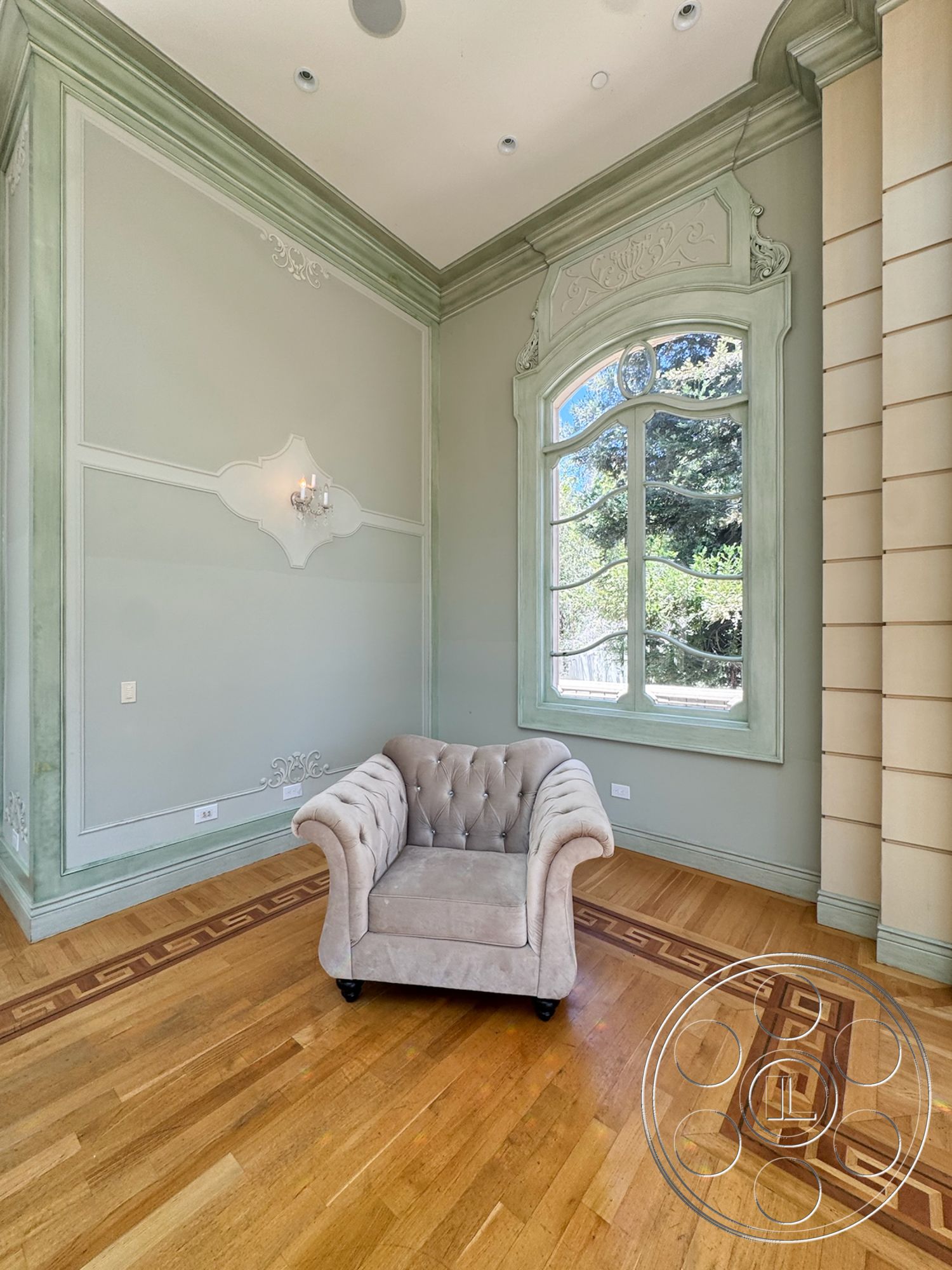 Tiffany Estate - arched doorways, traditional architectural style, recessed ceiling lights, crown molding details, plastered wall finish, hardwood flooring with geometric inlay, brown tufted armchair, light green wall treatment with decorative molding, ornate window frame with multi-pane glass