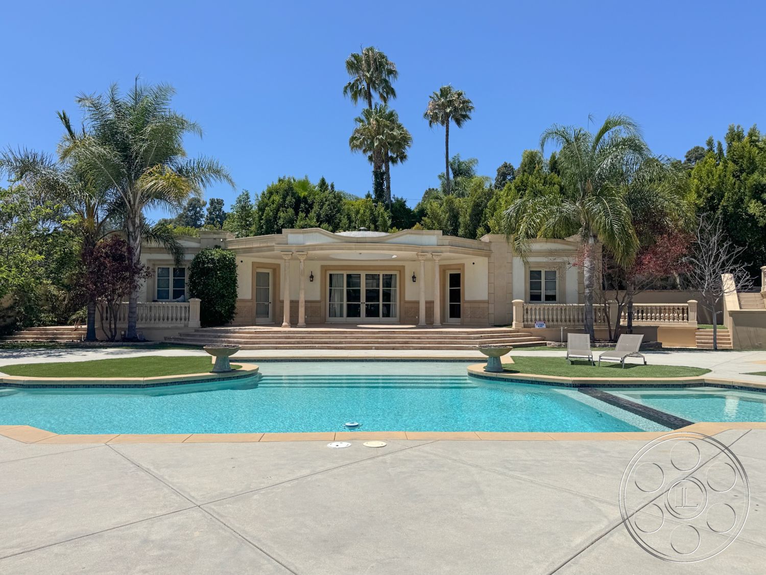 Tiffany Estate - exterior, palm trees, glass sliding doors, rectangular swimming pool, outdoor lounge area, concrete pool deck, landscaped garden area, stucco exterior walls, modern ranch-style home, surrounding tropical vegetation, sunny backyard setting, low-maintenance grass lawn, stone steps leading to house, decorative balcony railings
