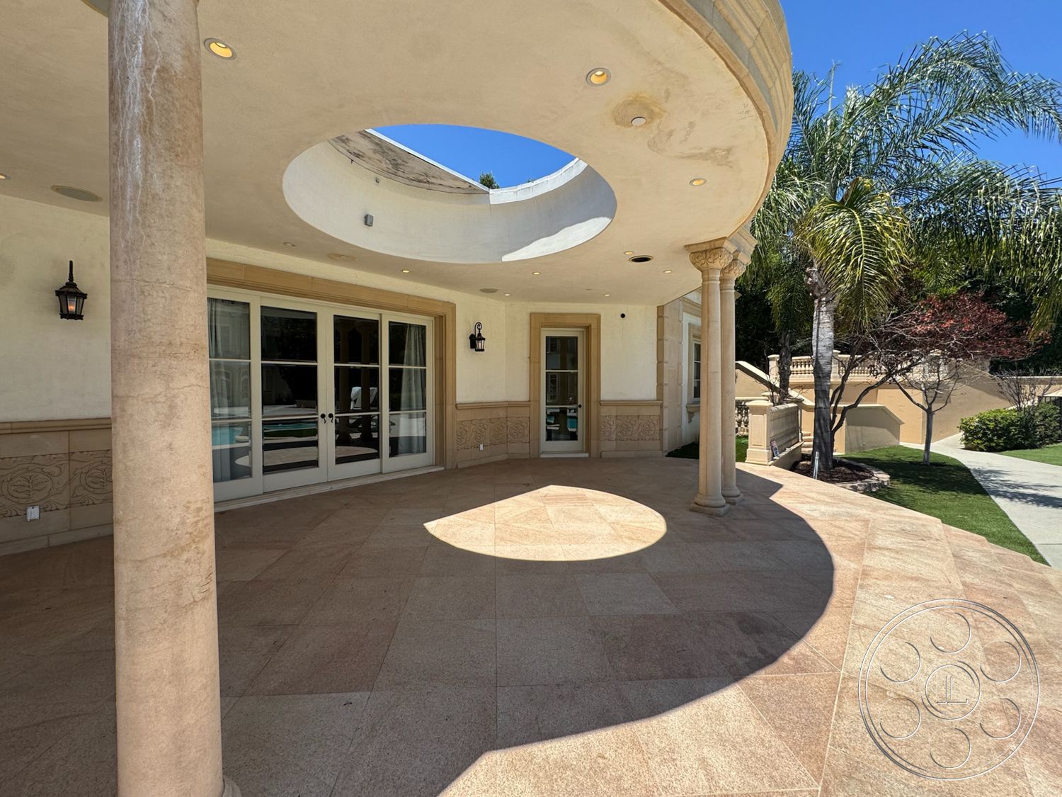 Tiffany Estate - exterior, vaulted ceiling, tropical landscaping, arched doorways, textured plaster walls, luxury outdoor space, large sliding glass doors, outdoor lighting fixtures, stone patio flooring, curved patio, round skylight, decorative stone detailing, exposed column support