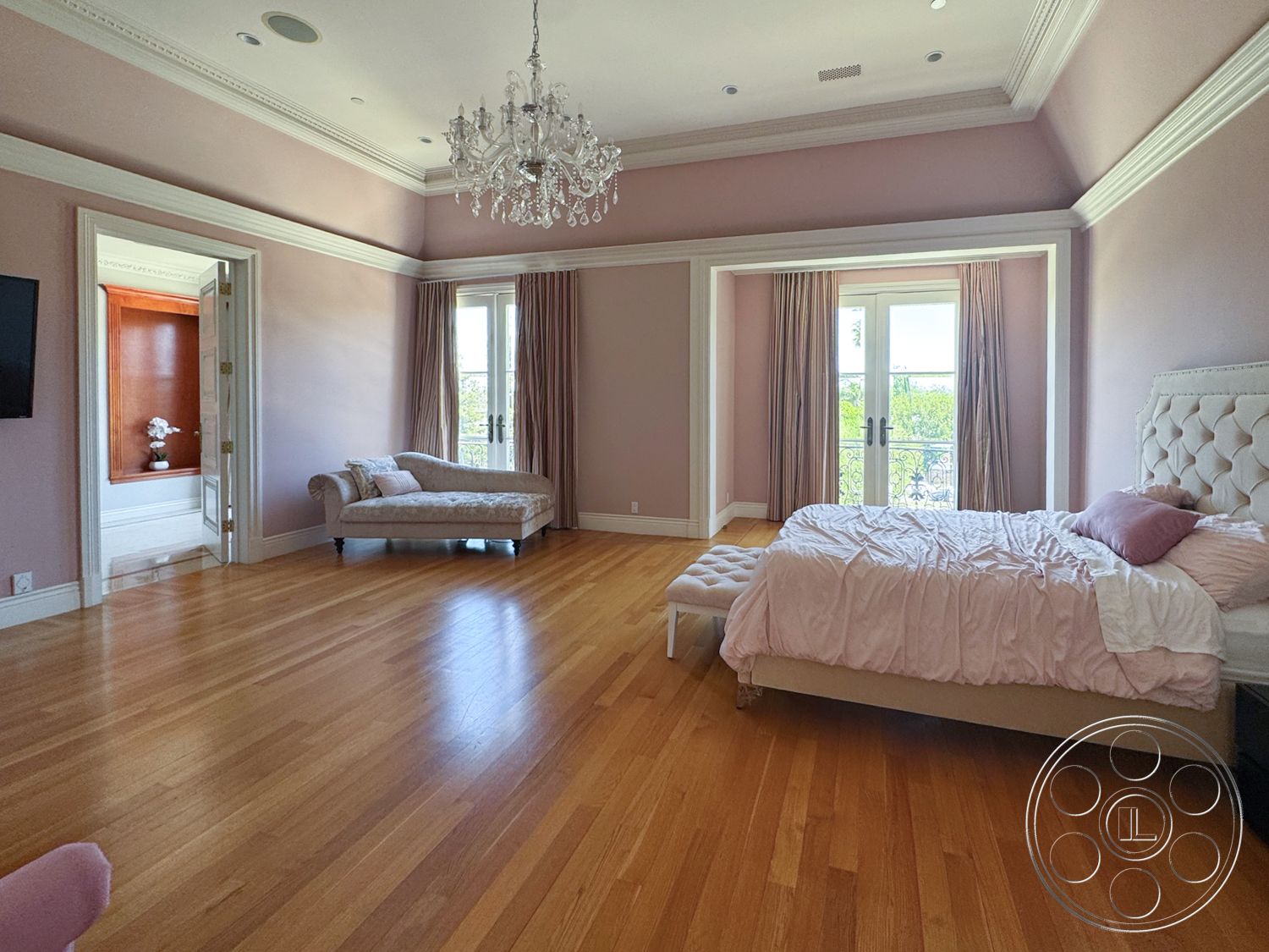 Tiffany Estate - floor-to-ceiling windows, hardwood bedroom floors, chandelier lighting fixture, exposed crown molding details, modern bedside table, pink painted walls, tufted headboard bed, curtains with rod, elegant chaise lounge
