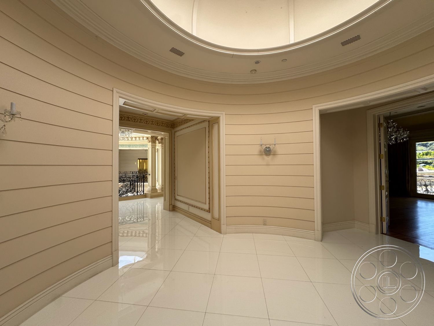 Tiffany Estate - high ceilings, arched doorways, decorative wall accents, luxurious entryway, crown molding details, chandelier lighting fixtures, glossy white tile flooring, rounded wall shape, textured beige wall paneling