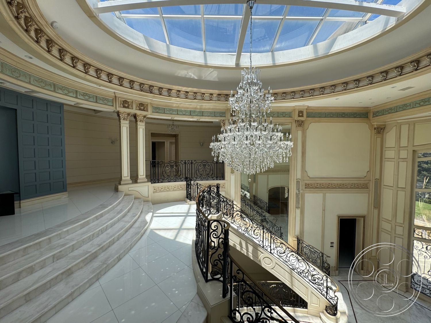 Tiffany Estate - neutral color palette, coffered ceiling, exposed wood beams, spiral staircase, marble flooring, curved wall design, glass skylight, decorative wall paneling, brass chandelier, intricate wrought iron railing, ornate crown molding, white marble steps, luxurious foyer area