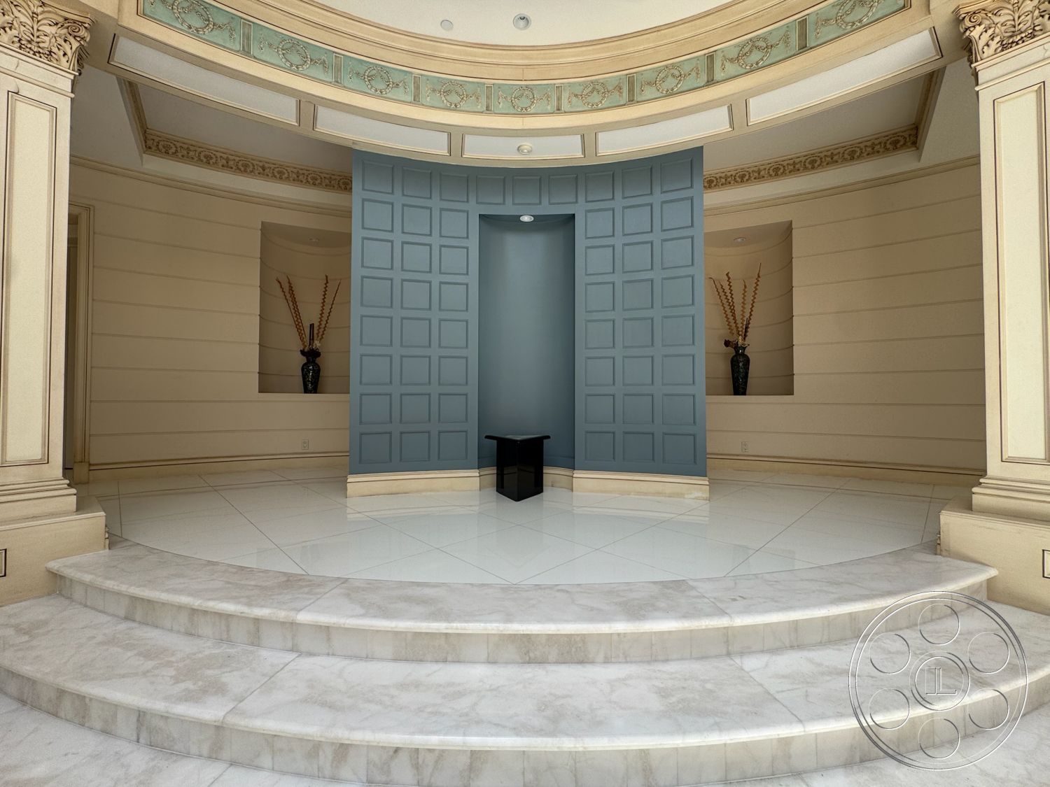 Tiffany Estate - soft overhead lighting, decorative crown molding, marble flooring, polished marble floor, painted accent wall, circular foyer, tall pedestal columns, built-in decorative niches, staircase with curved steps, vase decor on pedestals