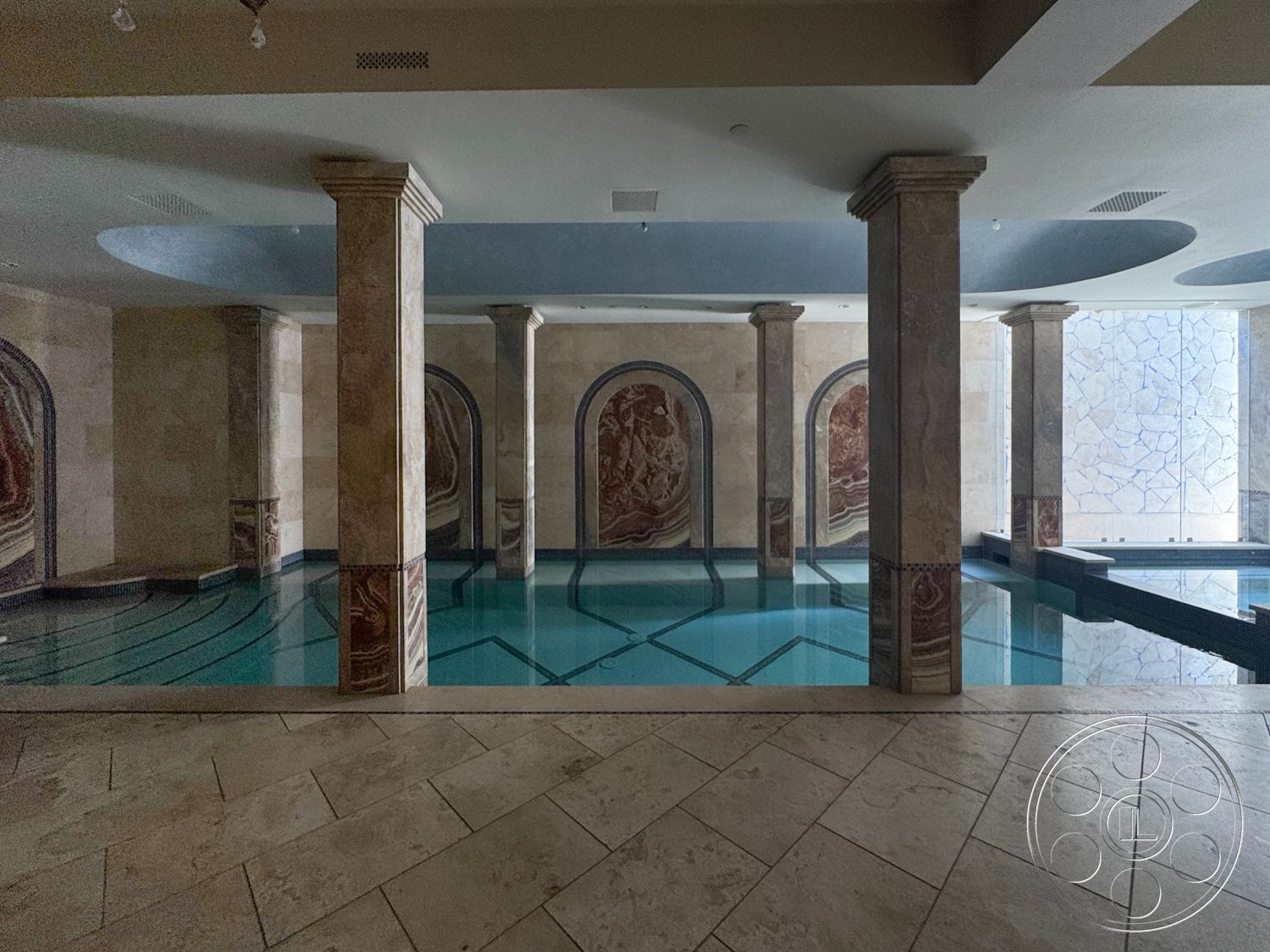 Tiffany Estate - rectangular swimming pool, textured wall panels, marble flooring, stone feature wall, decorative columns, artistic wall murals, interior swimming pool area, blue plaster ceiling, tile pool edging