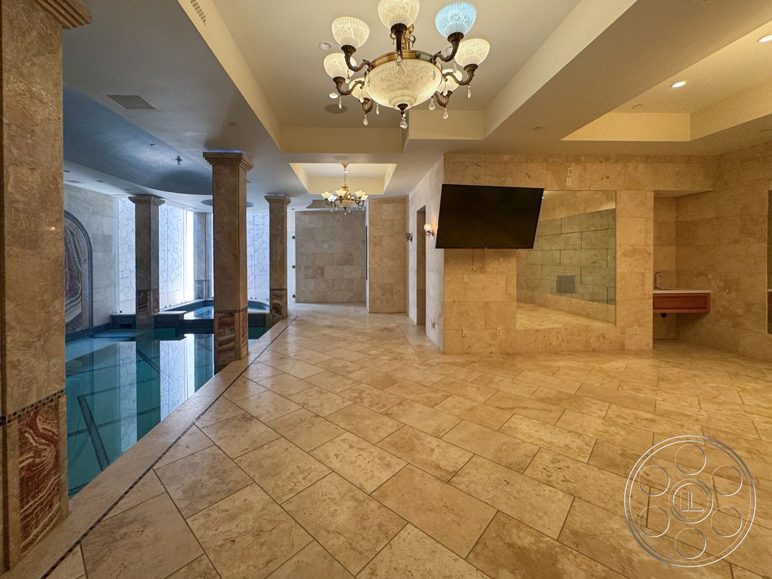 Tiffany Estate - recessed lighting, textured wall finishes, open floor plan layout, coffered ceiling details, chandelier light fixtures, travertine floor tiles, marble accent columns, rectangular indoor pool, glass wall details, integrated mirror wall, built-in sink cabinetry