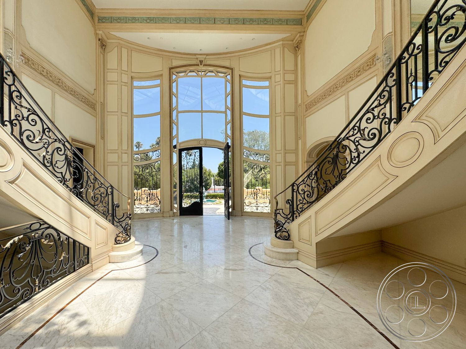Tiffany Estate - natural light from large windows, marble foyer flooring, curved staircase design, black wrought iron stair railings, decorative ceiling details, ornate wall paneling, arched entryway doors, tall floor-to-ceiling windows, intricate architectural crown molding, luxurious entry foyer, elegant double staircase, elegant window detailing, spacious entrance hall