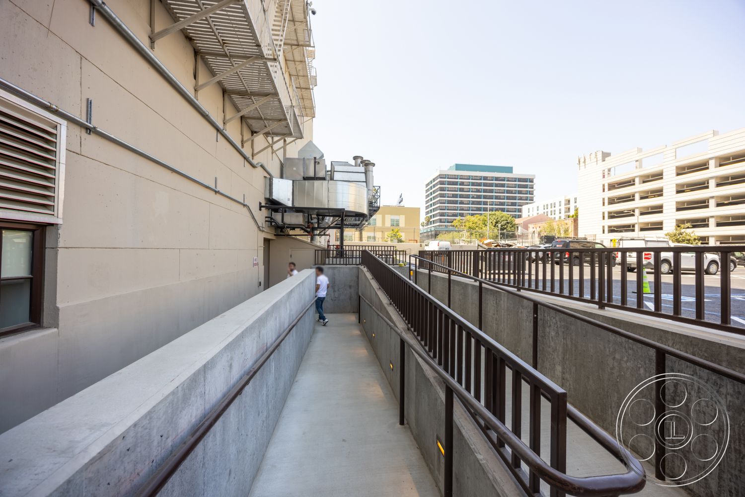 The Plaza - large windows, exterior, concrete walls, urban setting, steel railing, concrete walkway, ventilation system, industrial building features, surrounding parking structure, low-rise buildings in background
