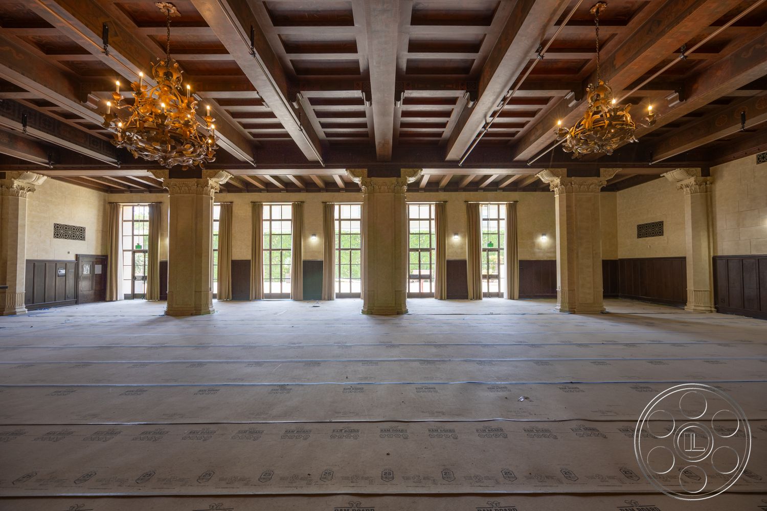 The Plaza - curtains, marble flooring, textured plaster walls, large arched windows, exposed wood ceiling beams, spacious open layout, wood paneling walls, chandelier lighting fixtures, classical architectural style, stone column bases