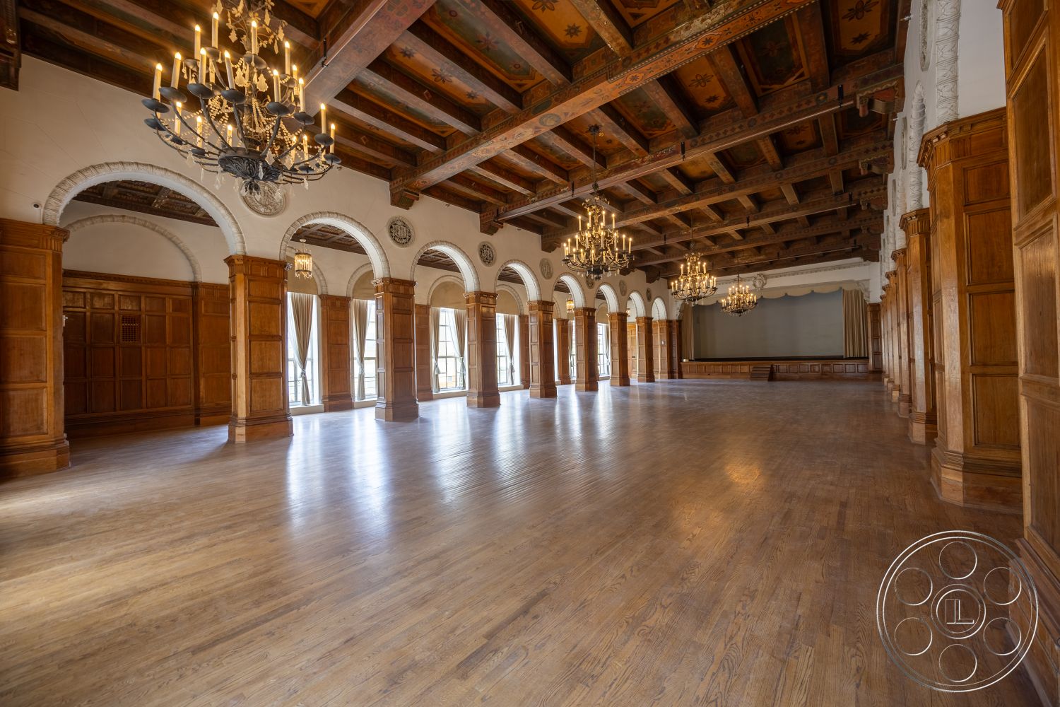 The Plaza - hardwood flooring, modern lighting fixtures, interior space, arched doorways, exposed wood ceiling beams, dark wood paneling walls, historic architectural style, ornate chandelier lighting, decorative ceiling details, elegant gathering area, tall windows with drapery, wainscoting wood panels