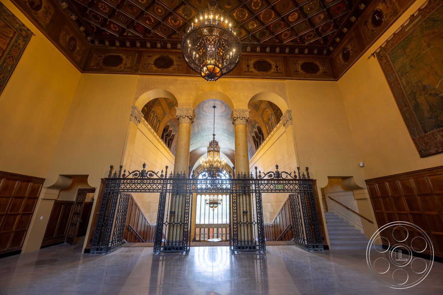 The Plaza - large arched windows, chandelier light fixture, historical architectural details, marble foyer flooring, textured wall paint, wood wall paneling, ornate metal gate, vaulted ceiling with decorative tiles, finished wooden staircase, modern plaster wall treatment, ornamental light fixture, tapestry wall hangings