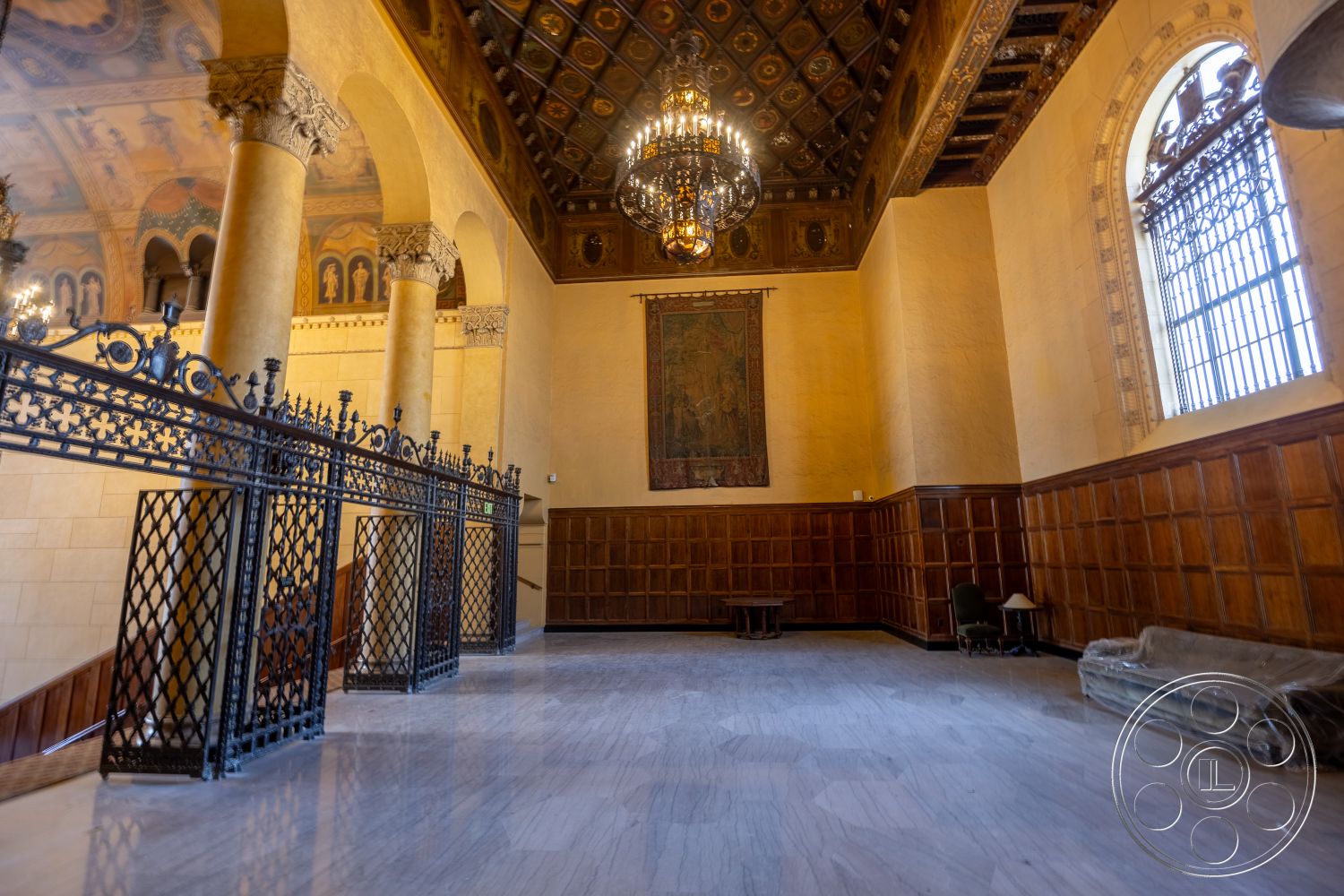 The Plaza - floor-to-ceiling windows, marble flooring, wrought iron railings, exposed wood paneling, ornate coffered ceiling, tapestry wall hanging, painted wall details, large chandelier