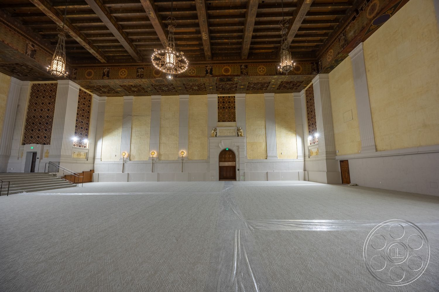 The Plaza - stone accent wall, carpet flooring, textured plaster walls, grand staircase, exposed wood ceiling beams, chandelier light fixtures, ornate ceiling detailing