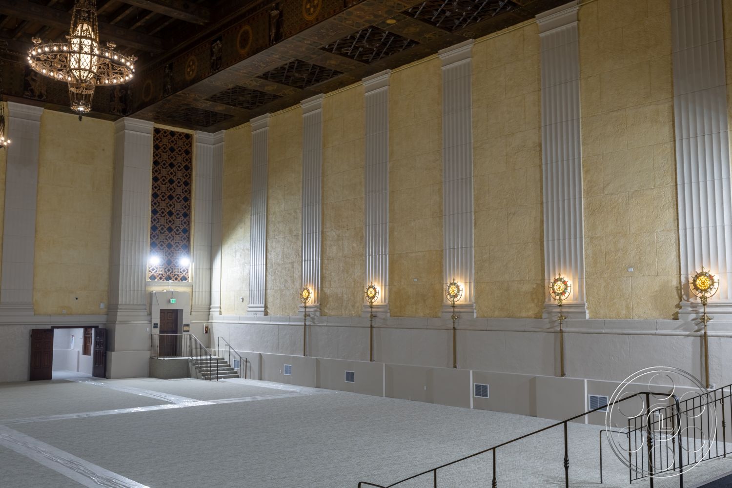 The Plaza - high ceilings, carpet flooring, textured plaster walls, grand staircase, decorative wall paneling, exposed wood ceiling beams, ornate chandelier lighting, art deco architectural style, wainscoting details
