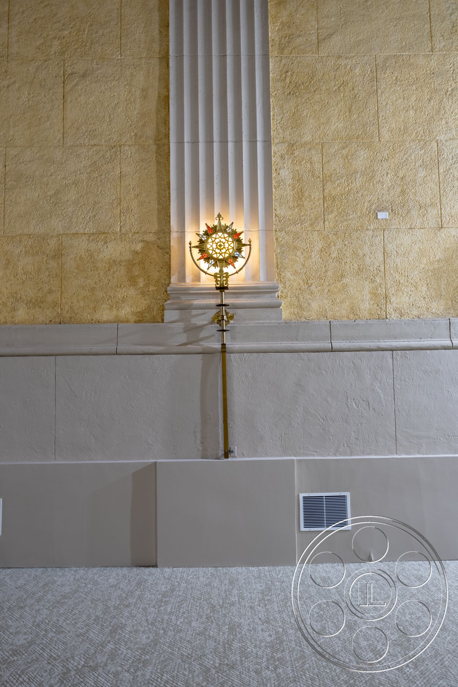 The Plaza - neutral color palette, architectural detailing, textured plaster wall, column with fluted detail, gold wall sconce fixture, beige baseboard trim, wool carpet flooring, classical style design