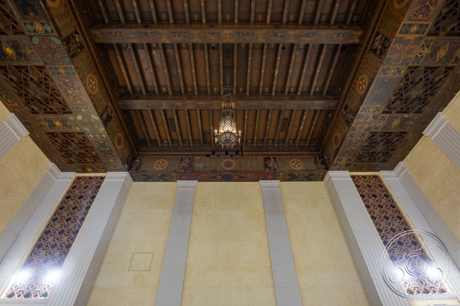 The Plaza - textured plaster walls, decorative wall paneling, architectural molding, exposed wood ceiling beams, chandelier lighting fixture, ornately painted ceiling tiles, column details