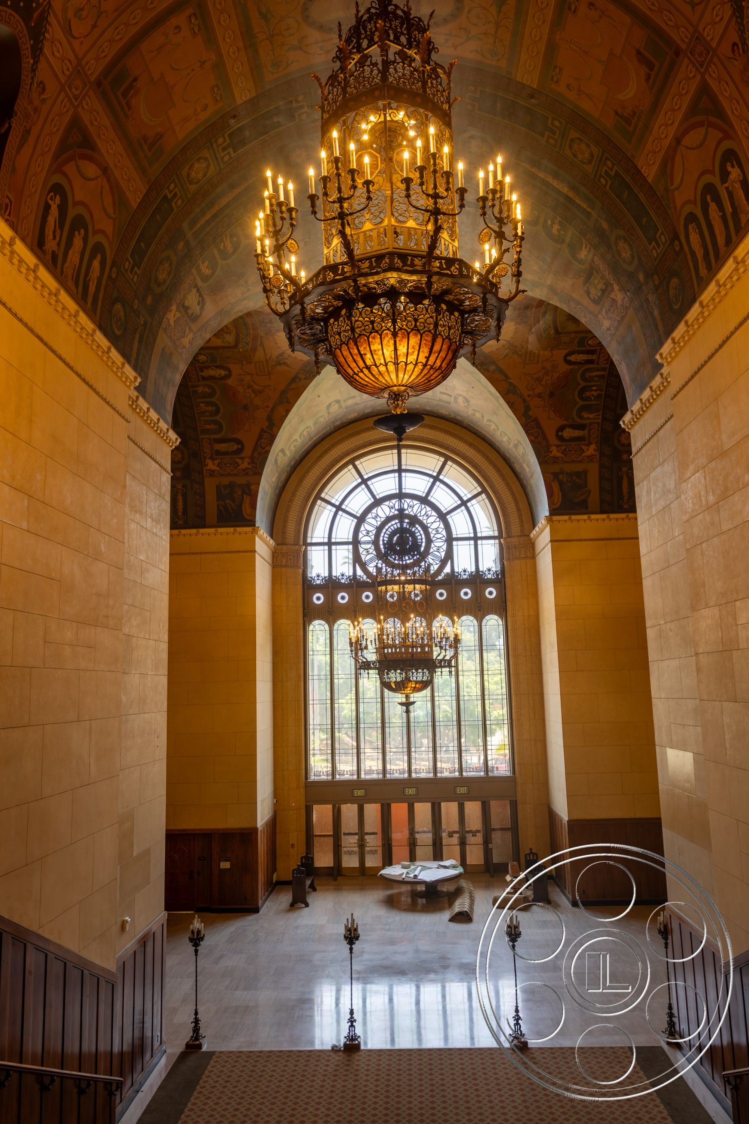 The Plaza - wood paneling, vaulted ceiling, wall sconces, reception area, marble flooring, large arched windows, ornate chandelier, grand entrance hall, natural light flooding in, historic architectural style, decorative ceiling molding