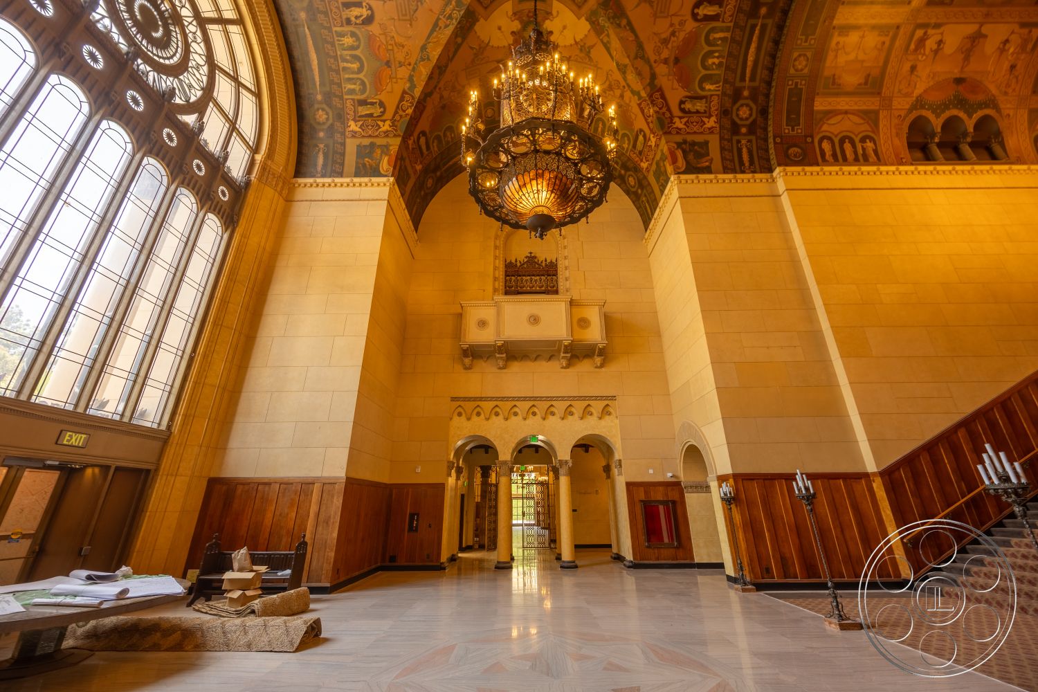 The Plaza - exterior, marble flooring, dark wood paneling, ornate chandelier, grand entrance hall, historic architectural style, vaulted entryway ceiling, arched glass entry windows, mural-painted ceiling, stone wall surfaces, intricate ceiling detailing, staircase with wooden handrail, decorative wall alcove, entry hall space