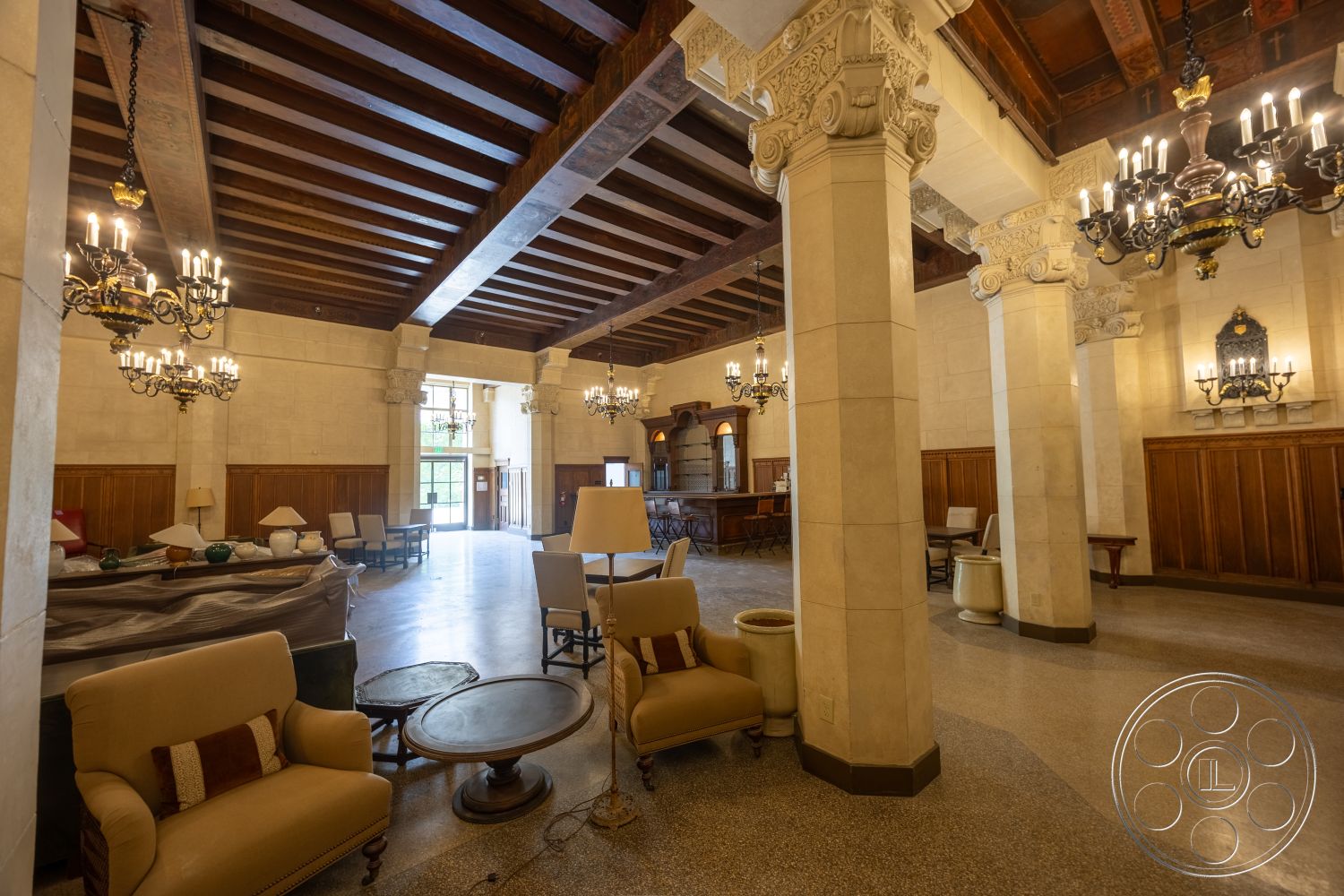 The Plaza - large windows, exterior, round coffee table, wood paneling, stone walls, parquet flooring, exposed wood ceiling beams, historic architectural style, chandelier lighting fixtures, ornate plaster ceiling details, traditional seating area, marble accent columns