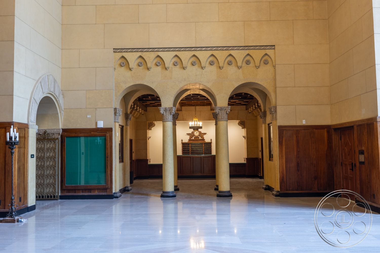 The Plaza - high ceilings, wood paneling, entryway, marble flooring, arched doorways, decorative tile details, historical architecture, stone columns, exposed wooden ceiling beams, yellow plaster walls, candle-style light fixture, ornate cornice detailing