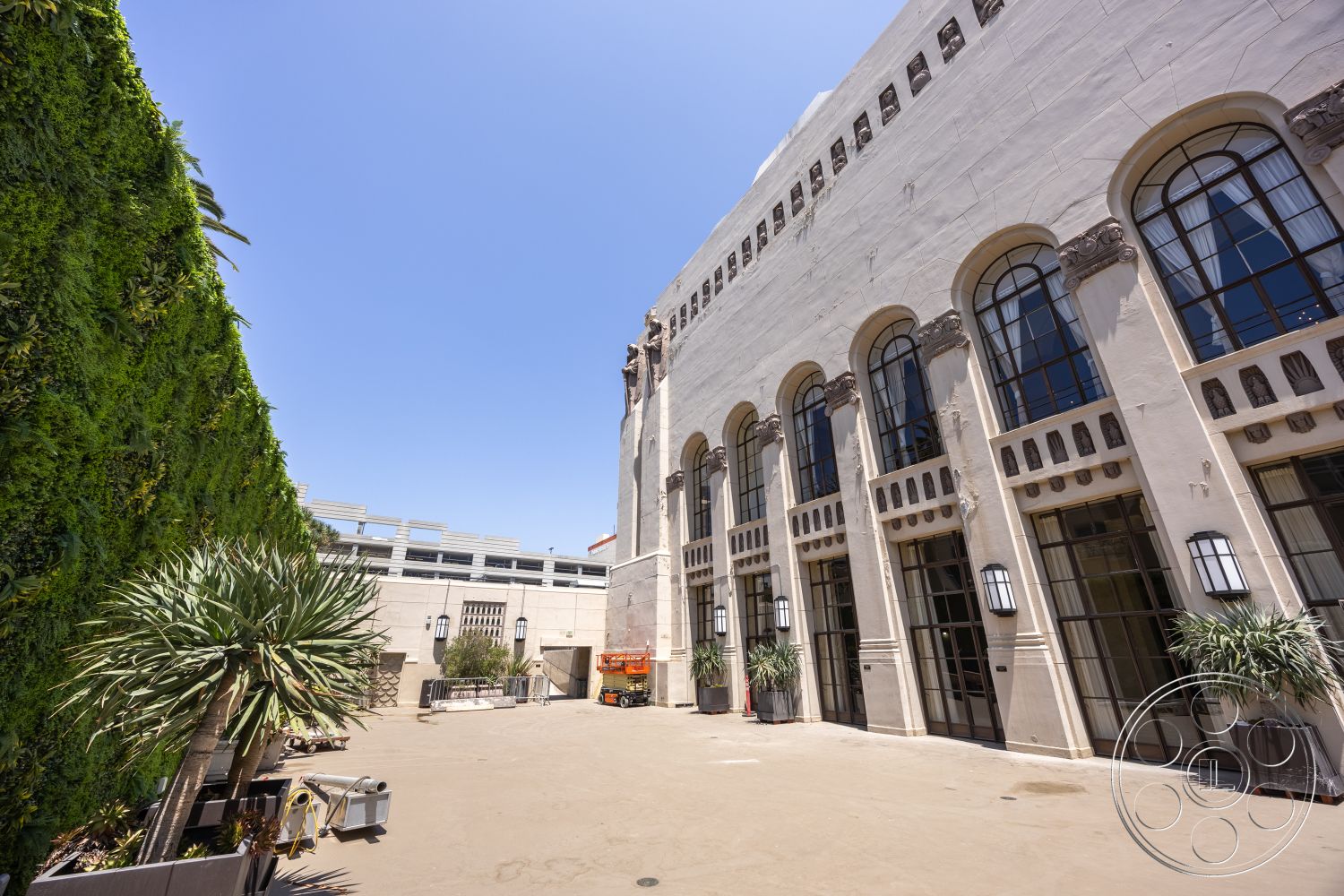 The Plaza - exterior, modern light fixtures, urban setting, drought-resistant landscaping, smooth stucco wall, metal framed windows, arched window designs, vertical garden wall, commercial building style, succulent plant arrangements, concrete courtyard flooring, decorative window lintels, paved entrance pathway, short palm trees