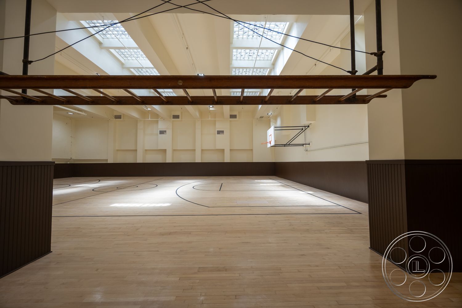 The Plaza - high ceilings, large open space, hardwood floor, basketball hoop, skylights, white painted walls, interior basketball court, exposed wooden beam, dark wainscoting, court markings