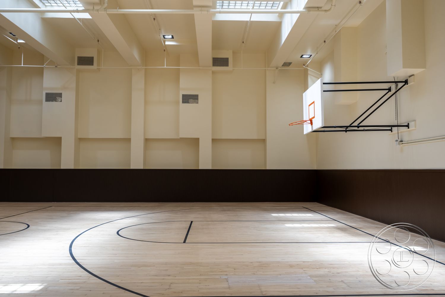 The Plaza - high ceiling, floor-to-ceiling windows, basketball hoop, dark wood paneling, exposed ceiling beams, flush-mounted ceiling lights, light-colored wall paint, hardwood gymnasium floor, wall-mounted basketball backboard