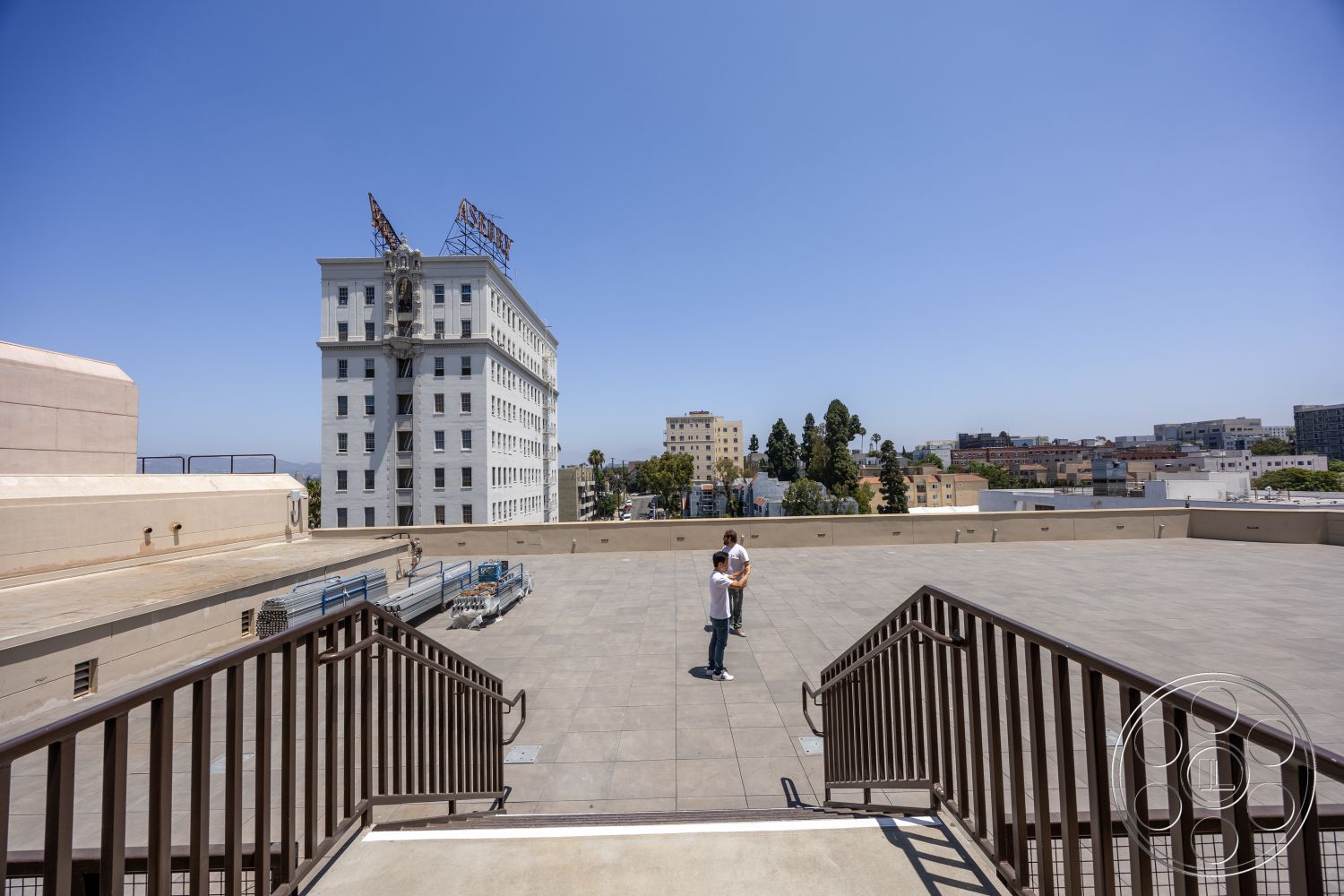 The Plaza - concrete flooring, flat roof structure, industrial architectural style, historic building facade, white painted brick walls, exterior roof terrace, rectangular rooftop layout, metal hand railing, urban cityscape view