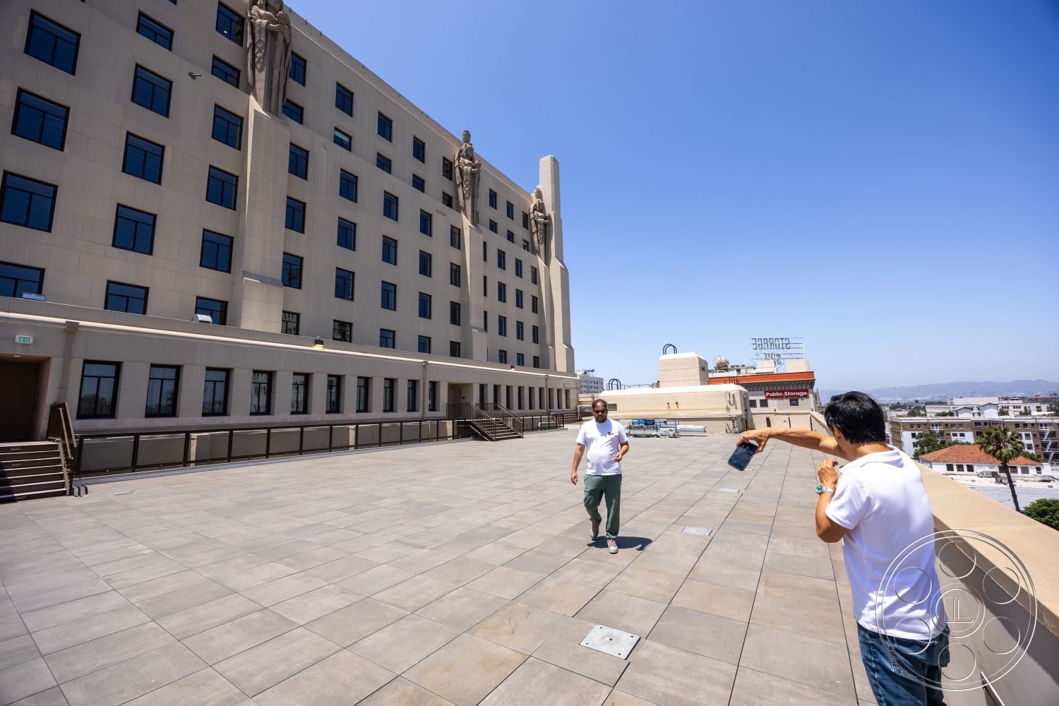 The Plaza - exterior, flat roof, metal railings, urban setting, roof terrace, city skyline view, concrete plaza flooring, art deco architectural style, glass window facades, structural concrete walls, decorative stone sculptures